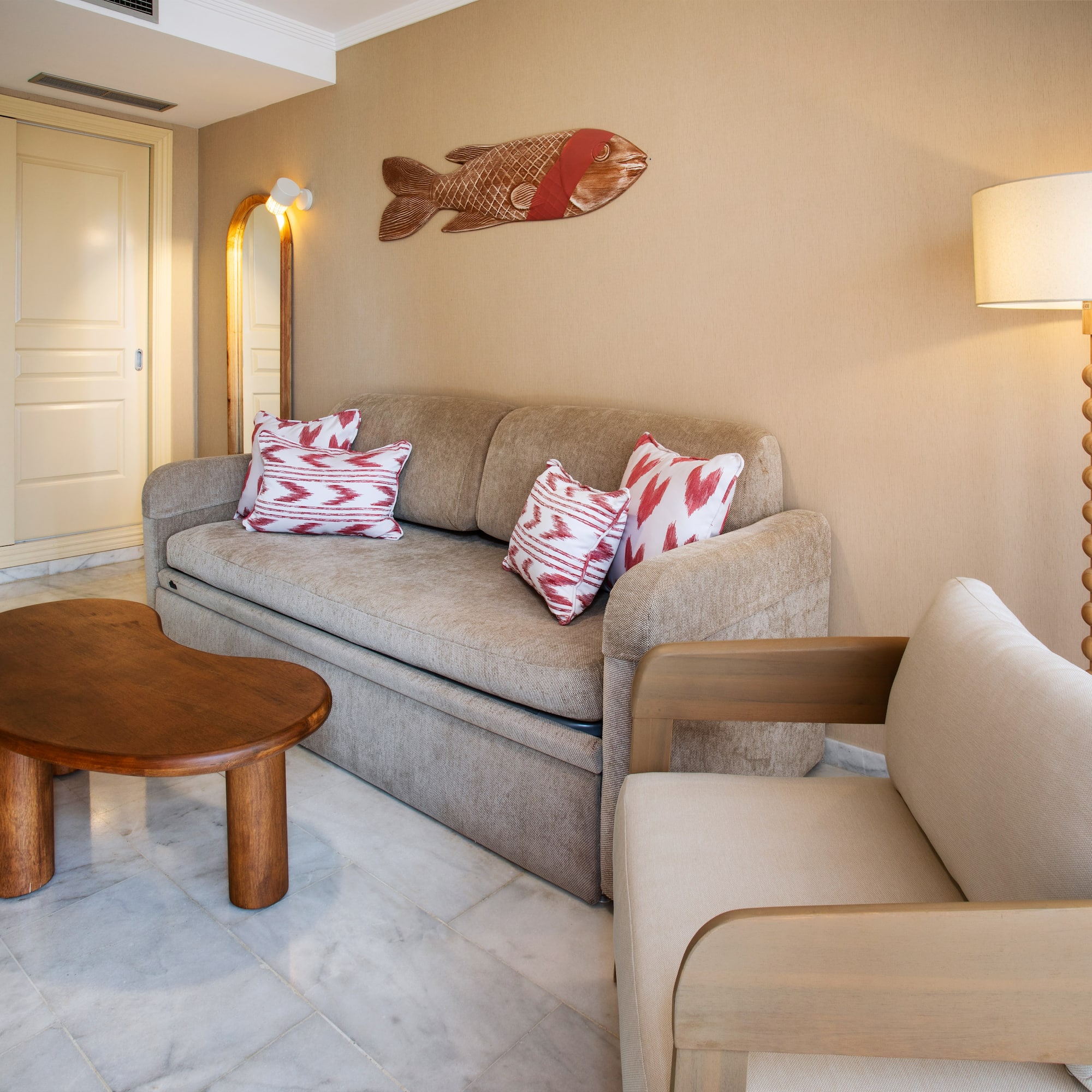 Cozy living room with beige sofa, wood table, armchair, and fish art.