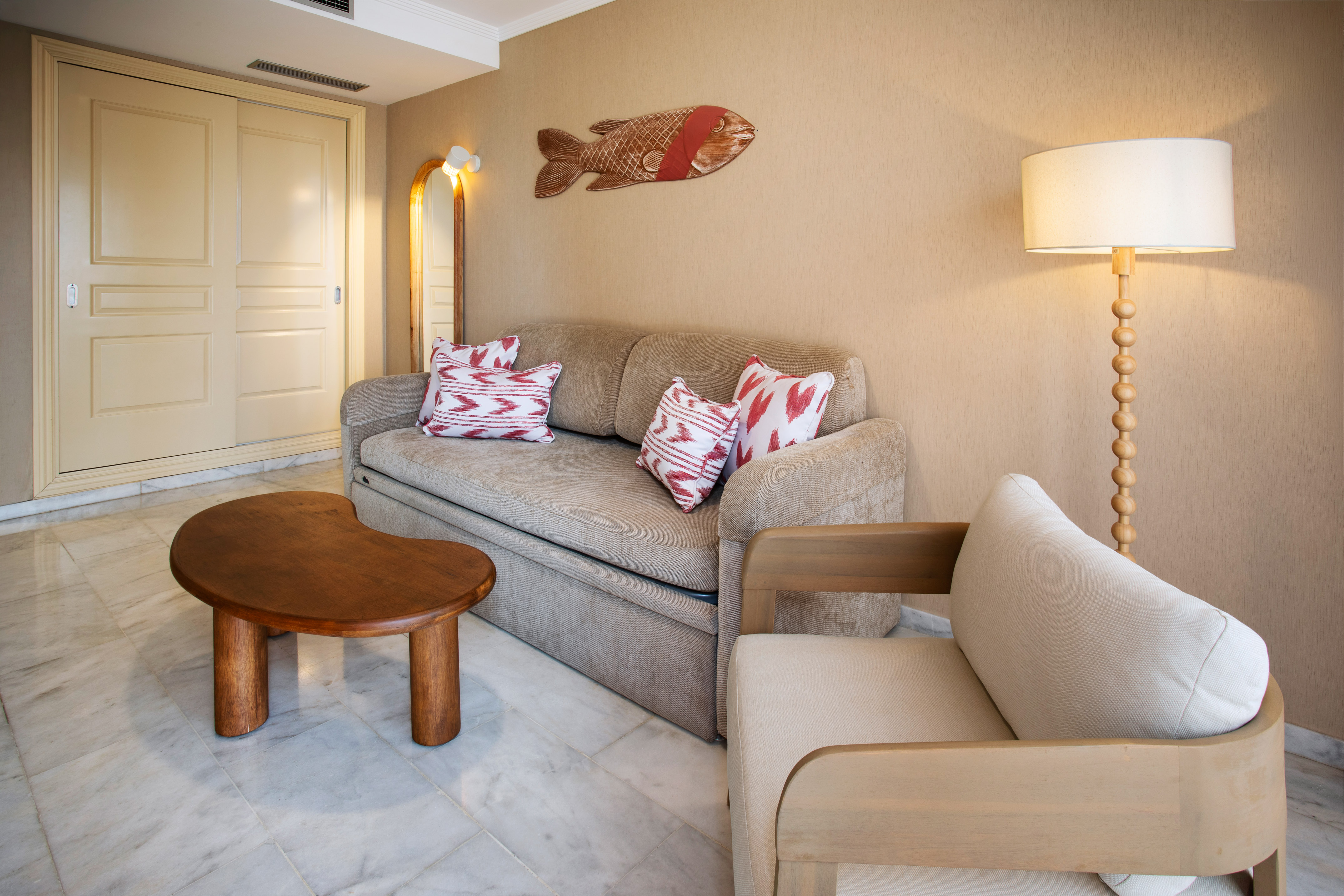 Cozy living room with beige sofa, wood table, armchair, and fish art.