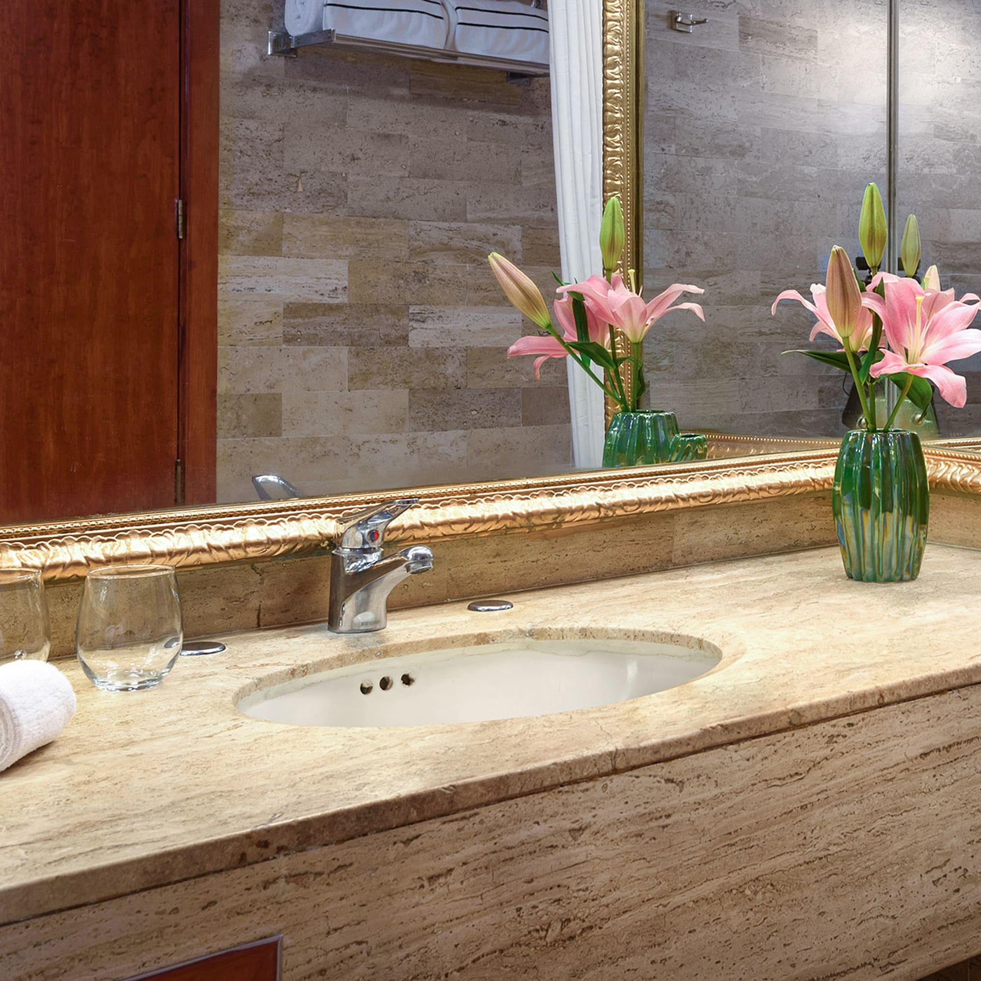 a bathroom sink with flowers and a mirror