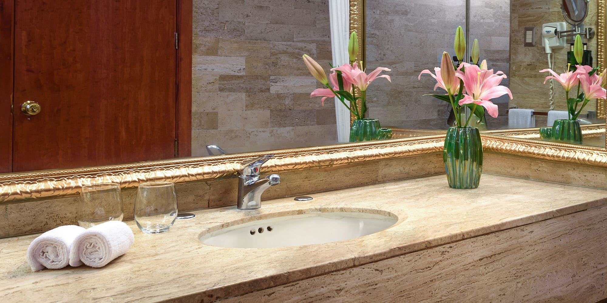 a bathroom sink with flowers and a mirror
