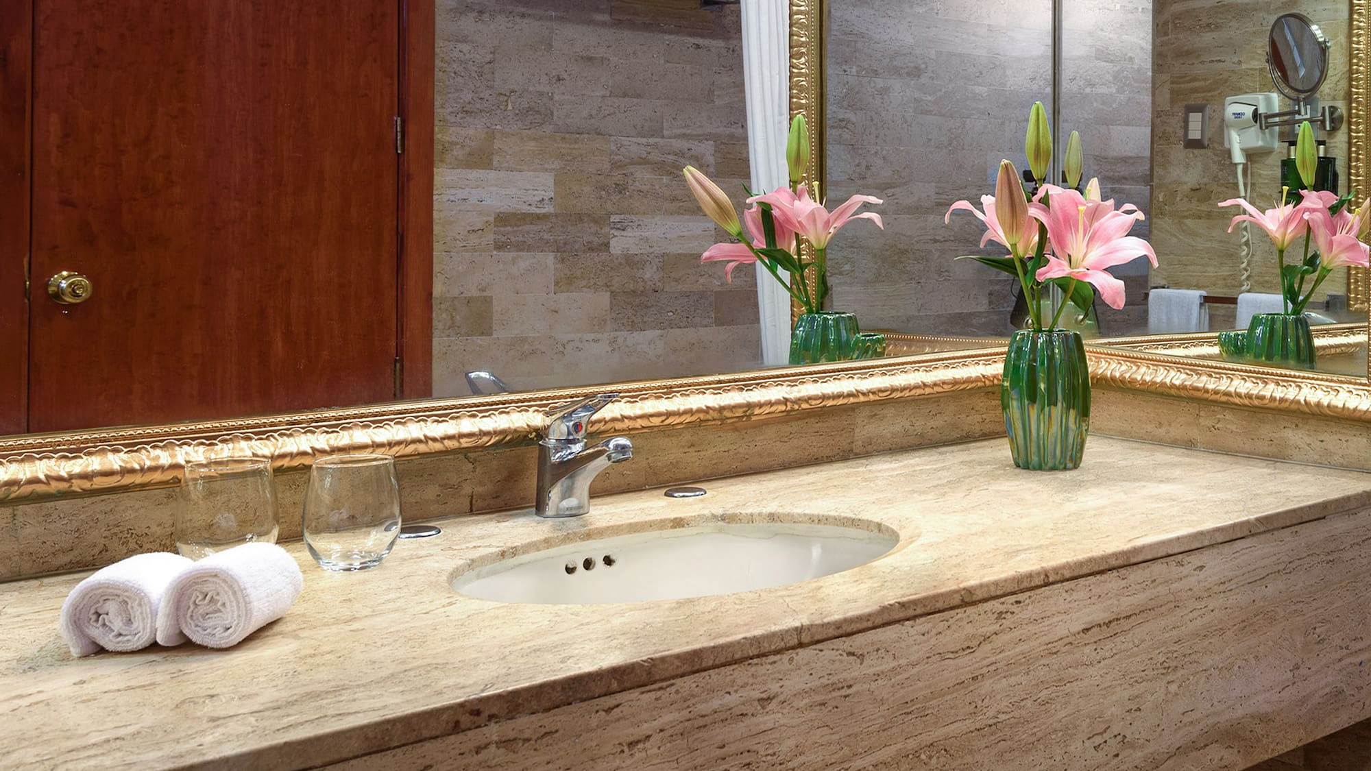 a bathroom sink with flowers and a mirror