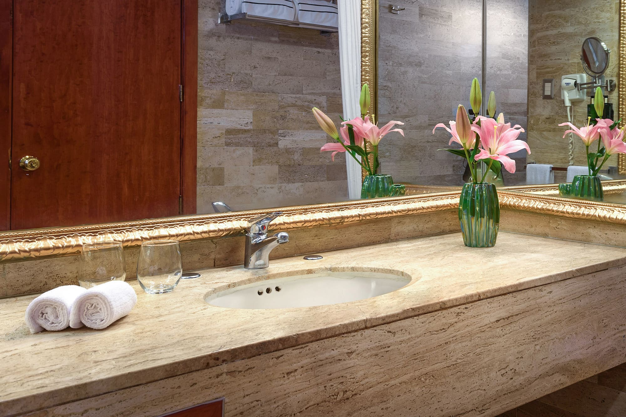 a bathroom sink with flowers and a mirror
