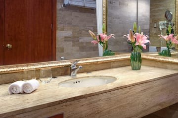 a bathroom sink with flowers and a mirror