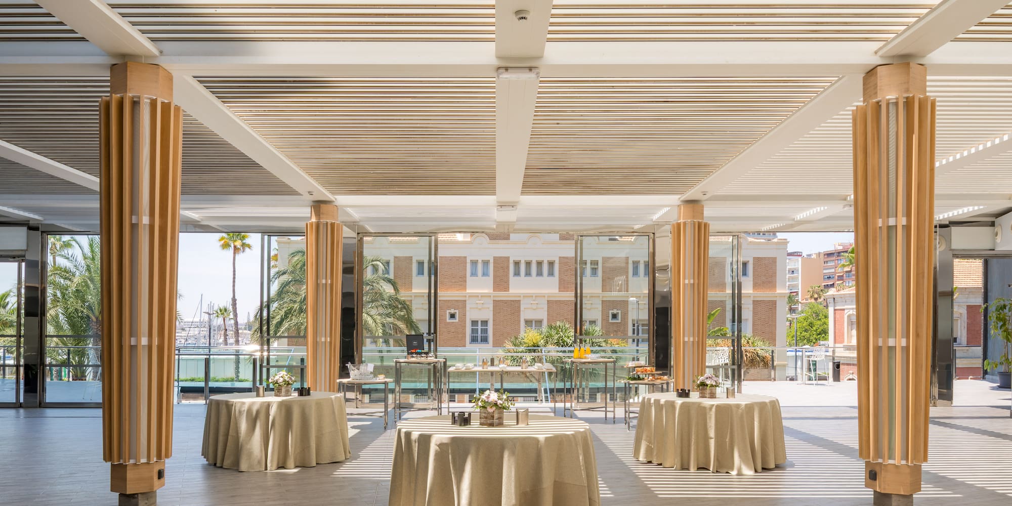 Elegant modern event venue with tables and sunny waterfront view.