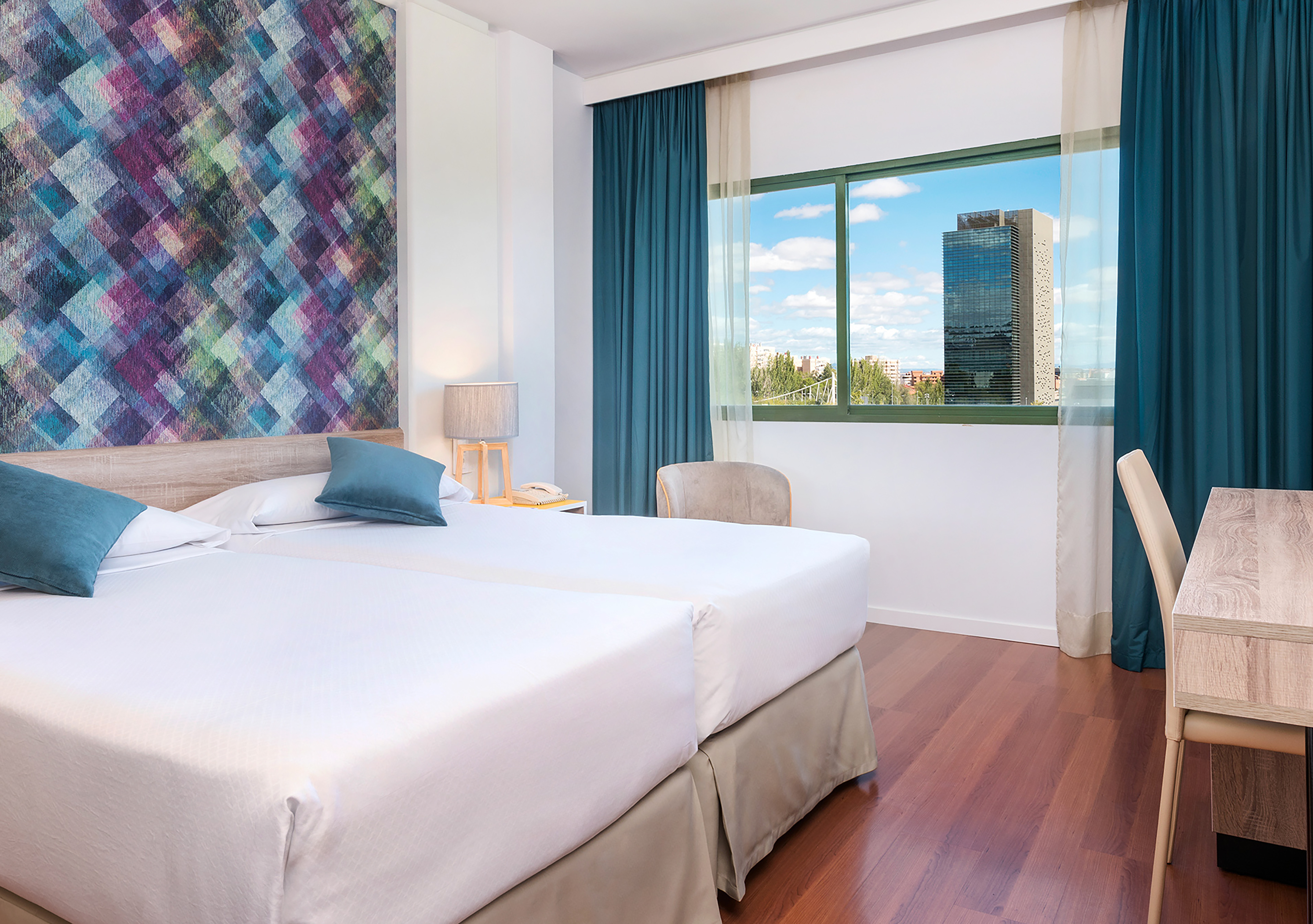 Comfortable hotel room with twin beds, patterned wall, city view.