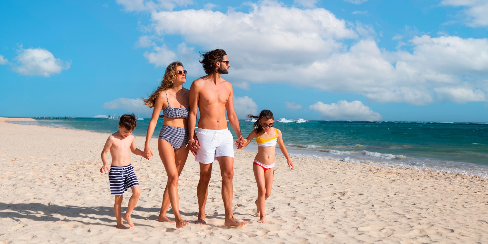 een man en een vrouw die elkaars hand vasthouden en op een strand lopen