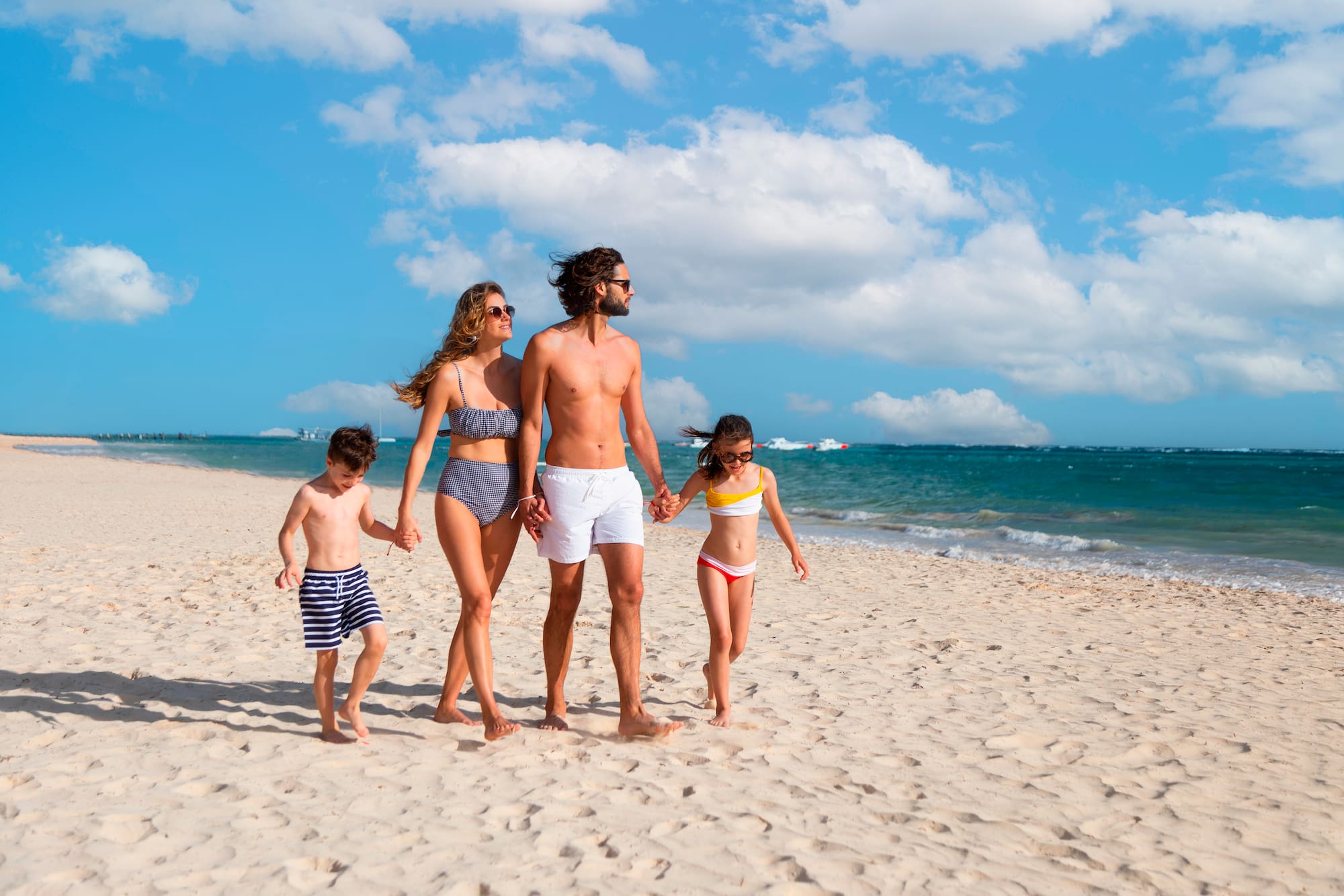 a man and woman holding hands and walking on a beach