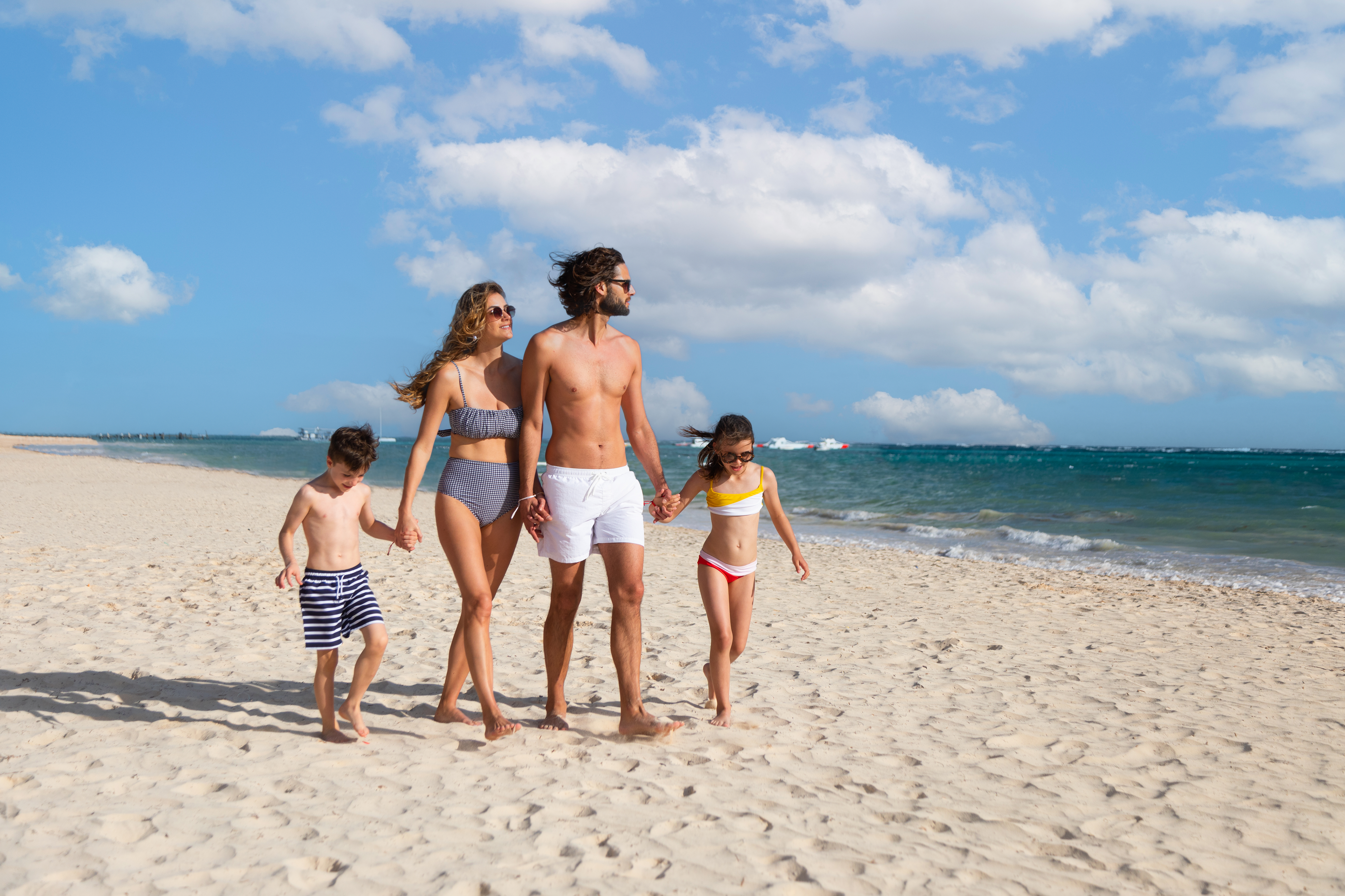 een man en een vrouw die elkaars hand vasthouden en op een strand lopen
