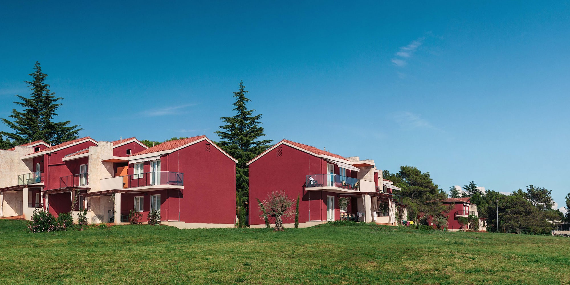 a group of red houses with grass and trees