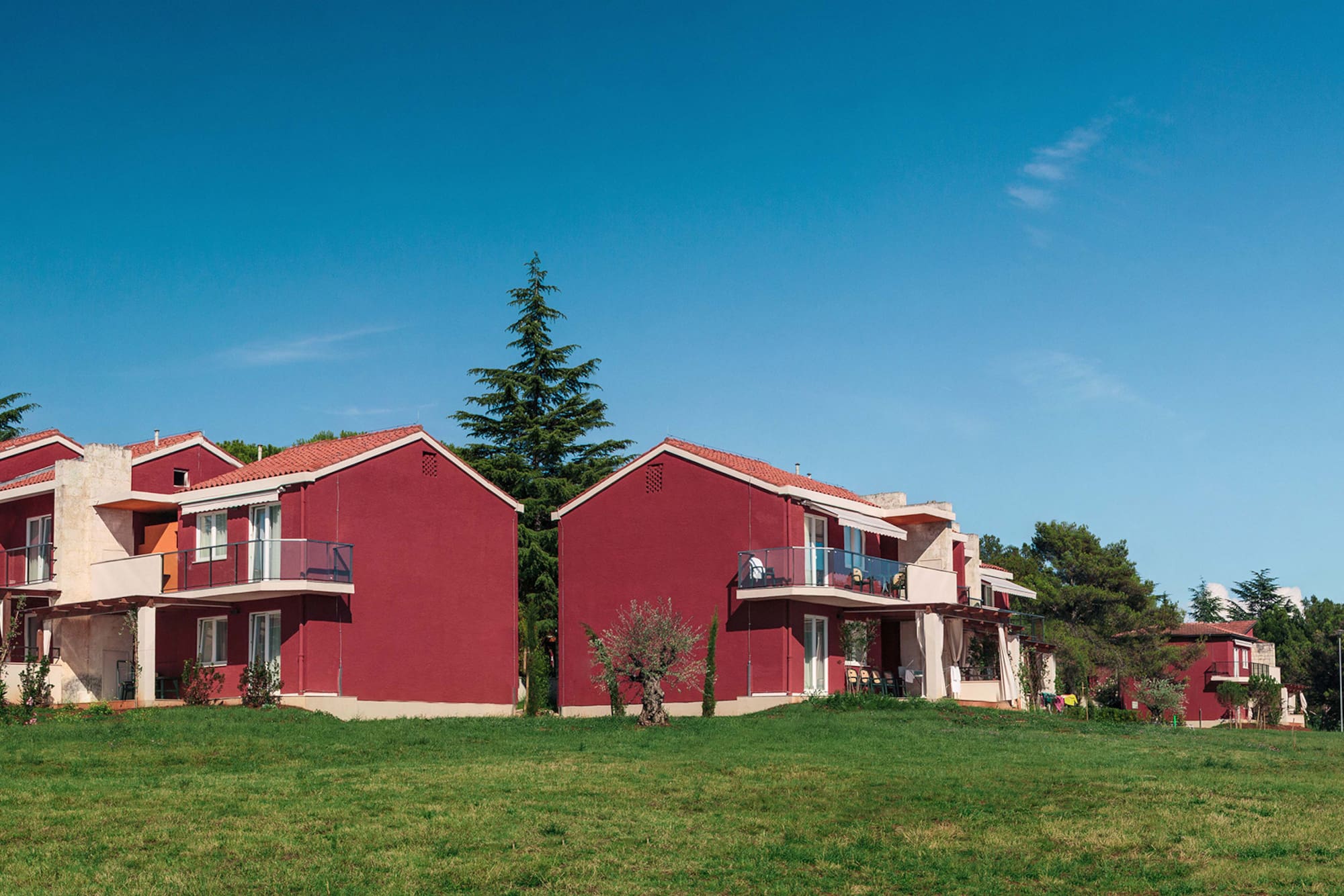 a group of red houses with grass and trees