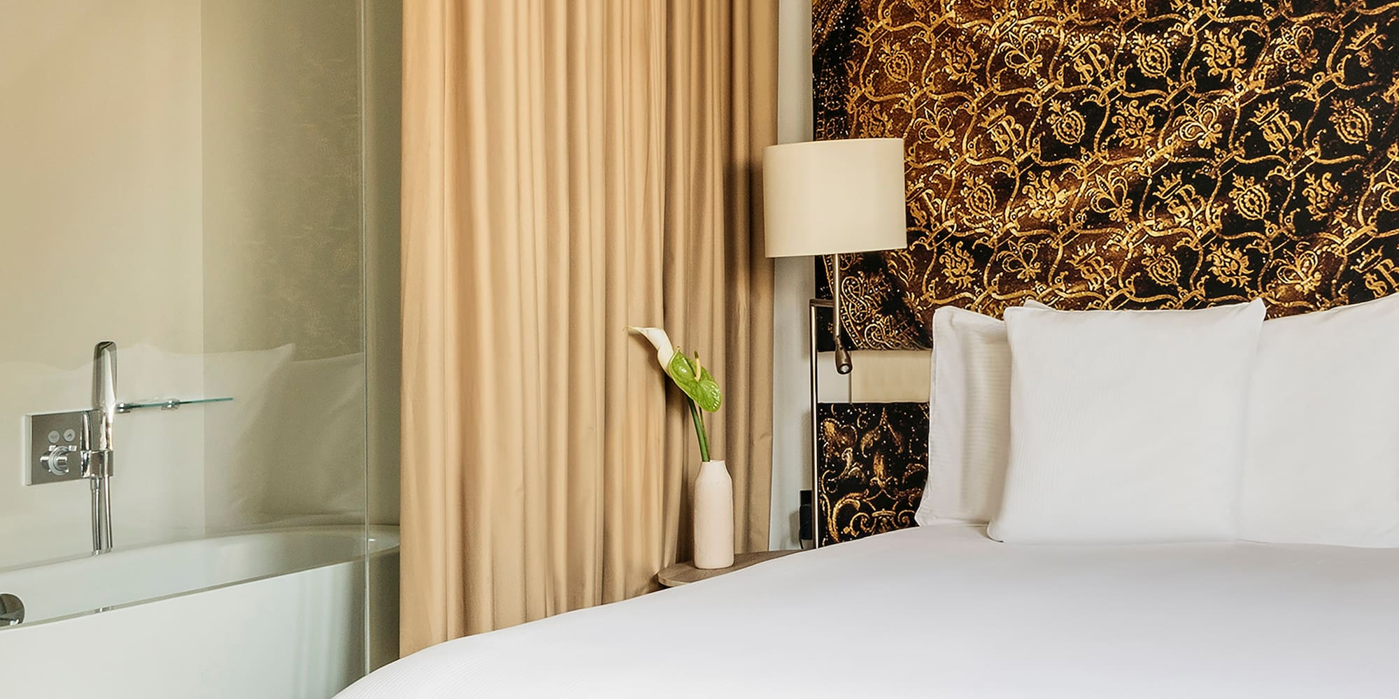 a bed with white sheets and a bathtub in a hotel room