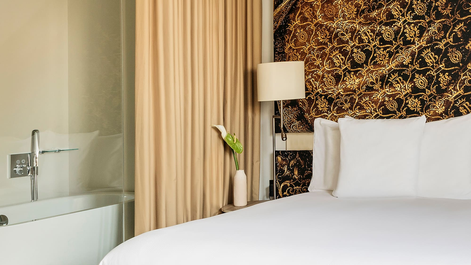 a bed with white sheets and a bathtub in a hotel room