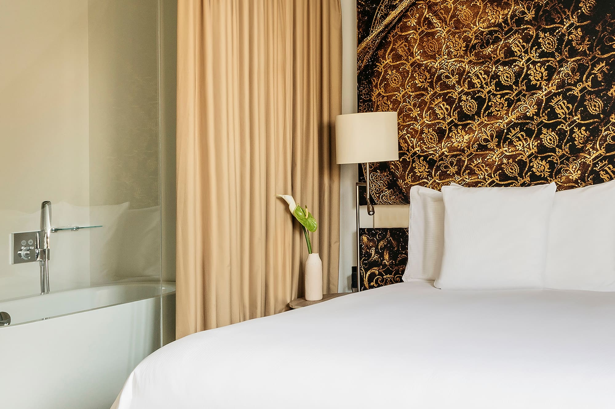 a bed with white sheets and a bathtub in a hotel room