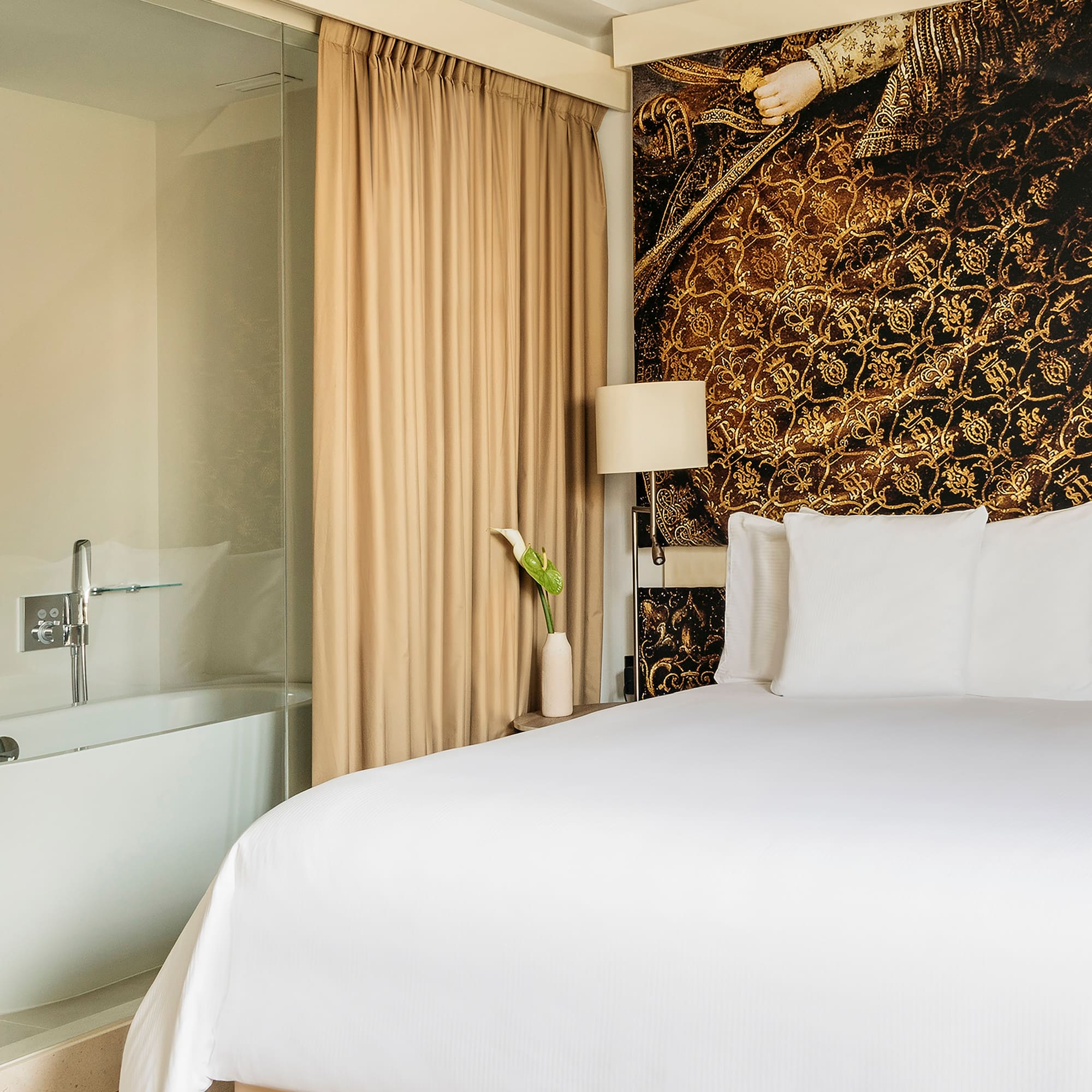 a bed with white sheets and a bathtub in a hotel room