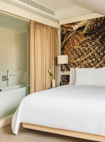 a bed with white sheets and a bathtub in a hotel room