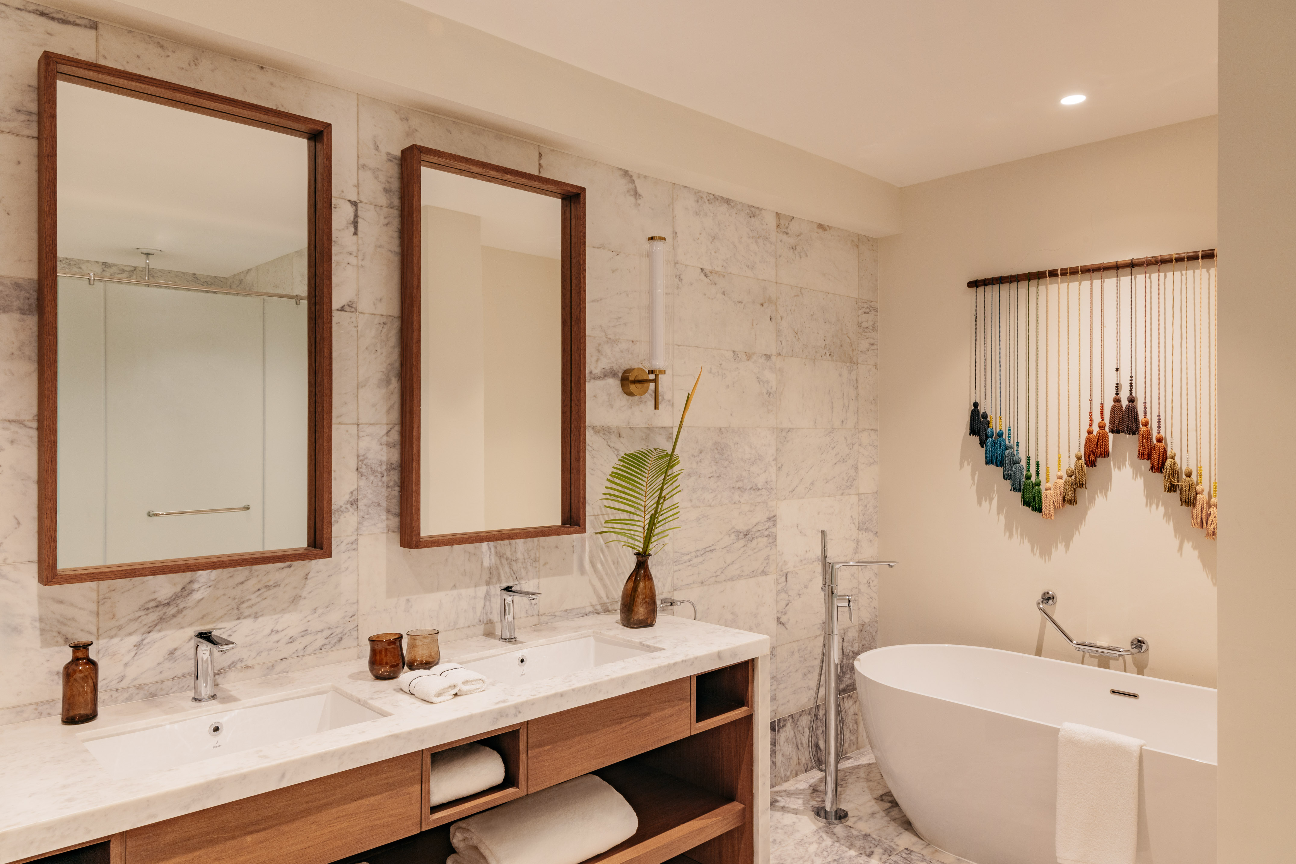 Modern marble bathroom with double vanity, wooden mirrors, freestanding tub.