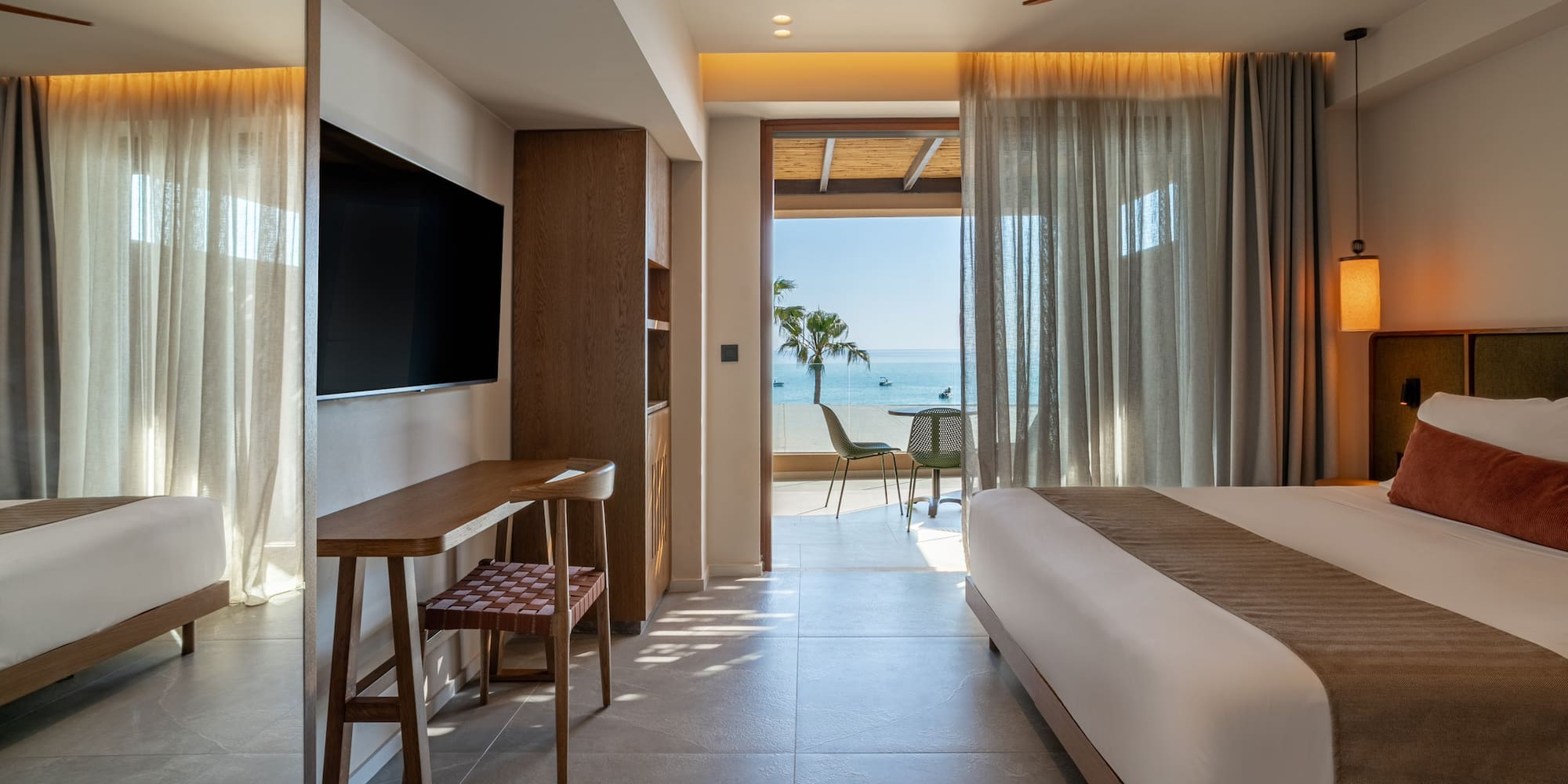Luxury hotel suite with modern decor, king bed, and ocean view balcony.