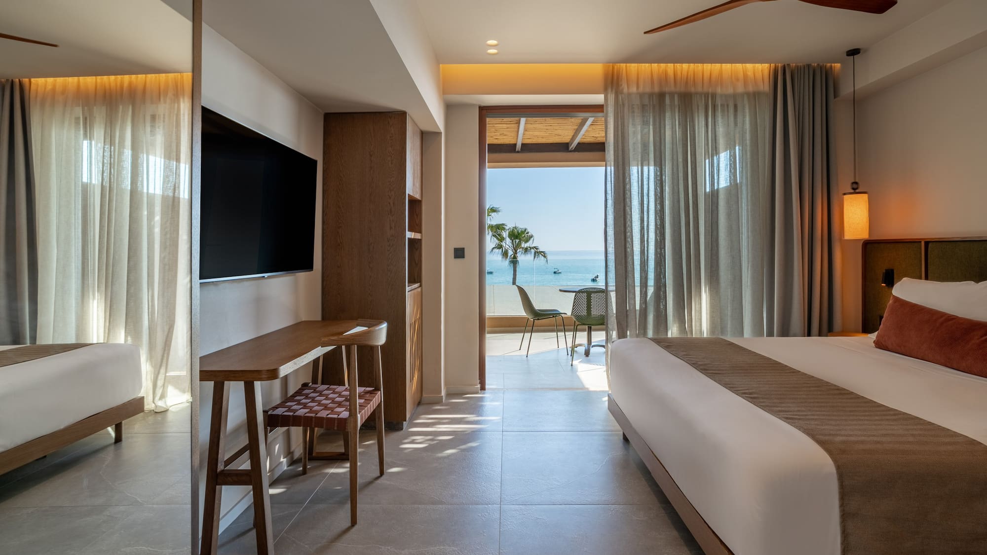 Luxury hotel suite with modern decor, king bed, and ocean view balcony.