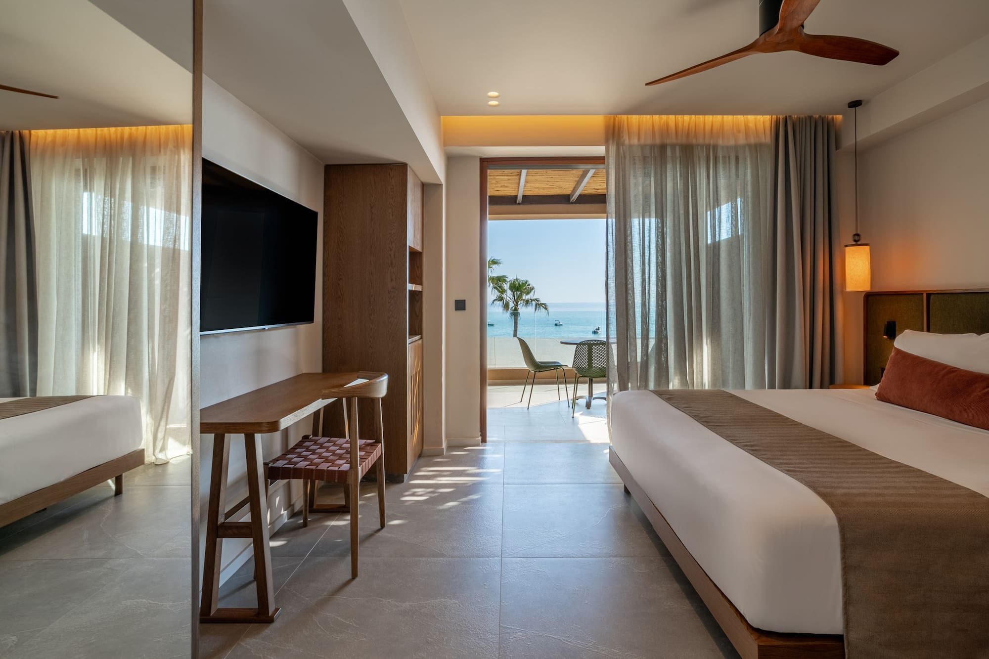 Luxury hotel suite with modern decor, king bed, and ocean view balcony.