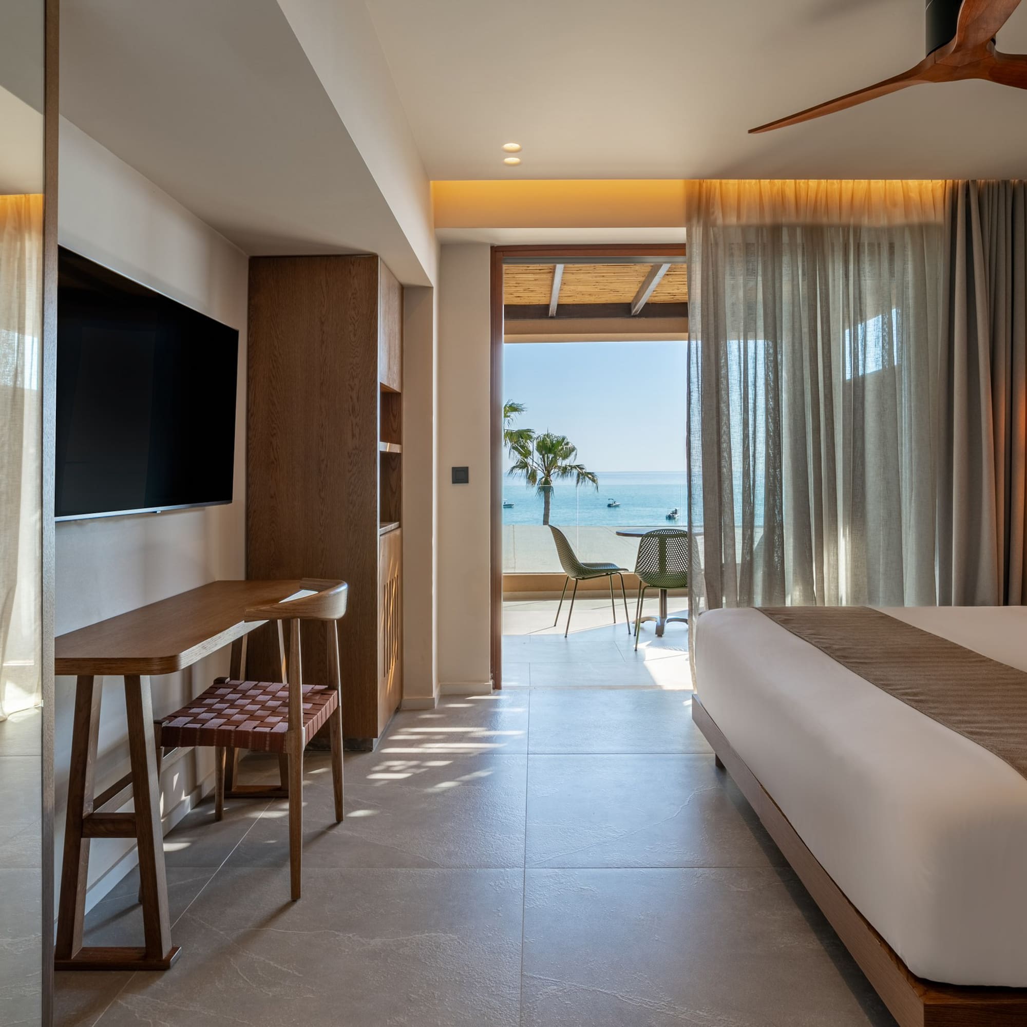Luxury hotel suite with modern decor, king bed, and ocean view balcony.