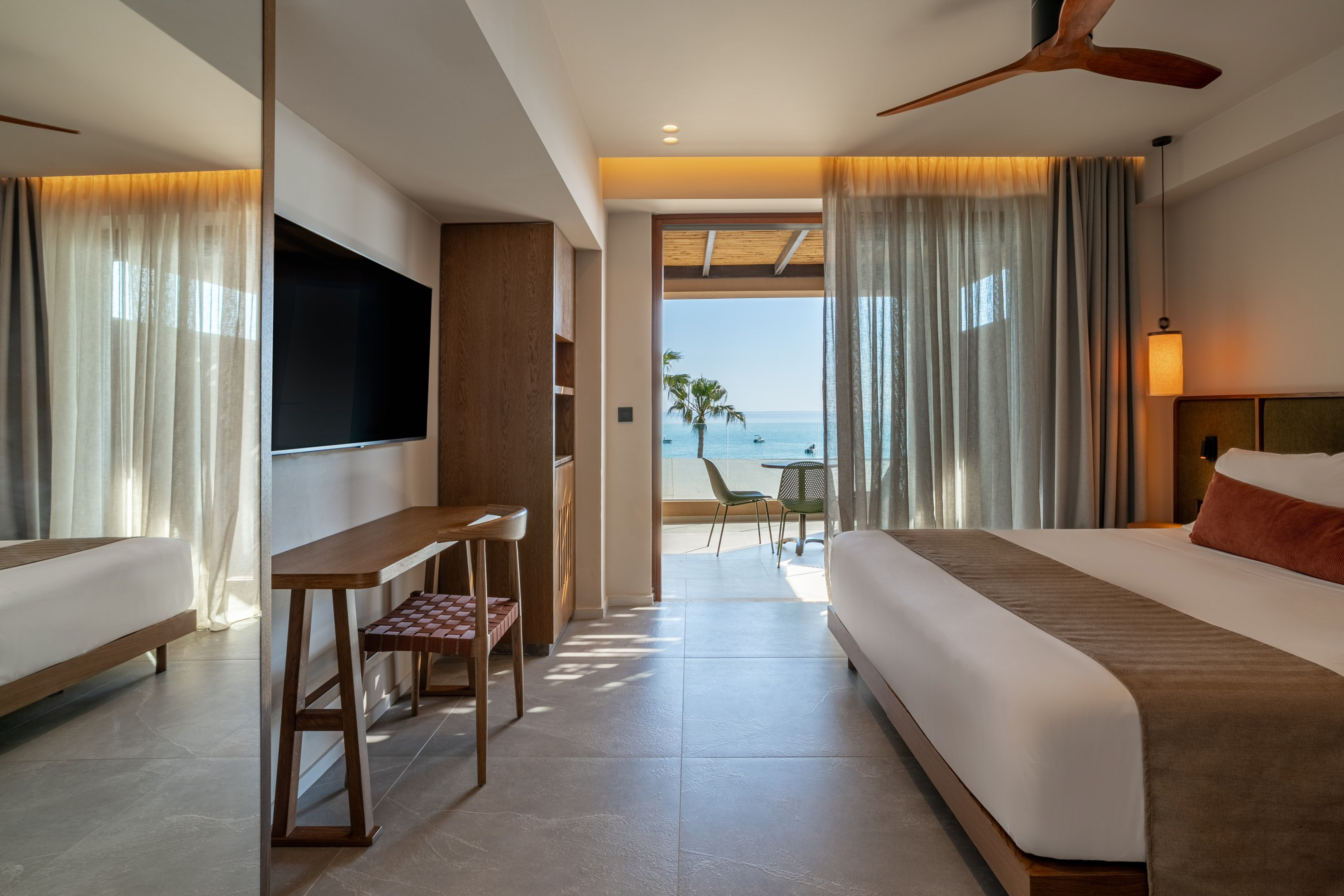 Luxury hotel suite with modern decor, king bed, and ocean view balcony.