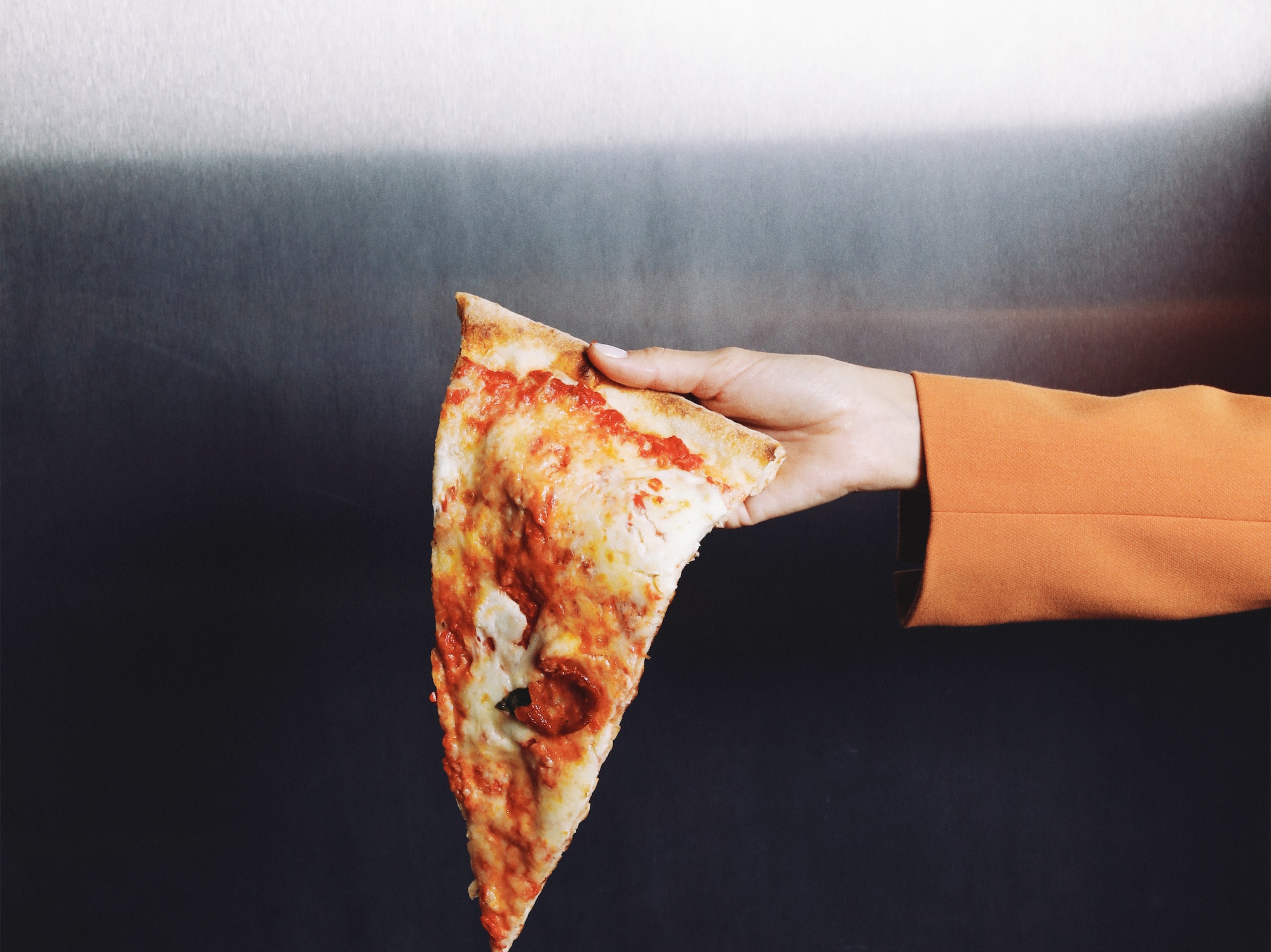 a hand holding a slice of pizza
