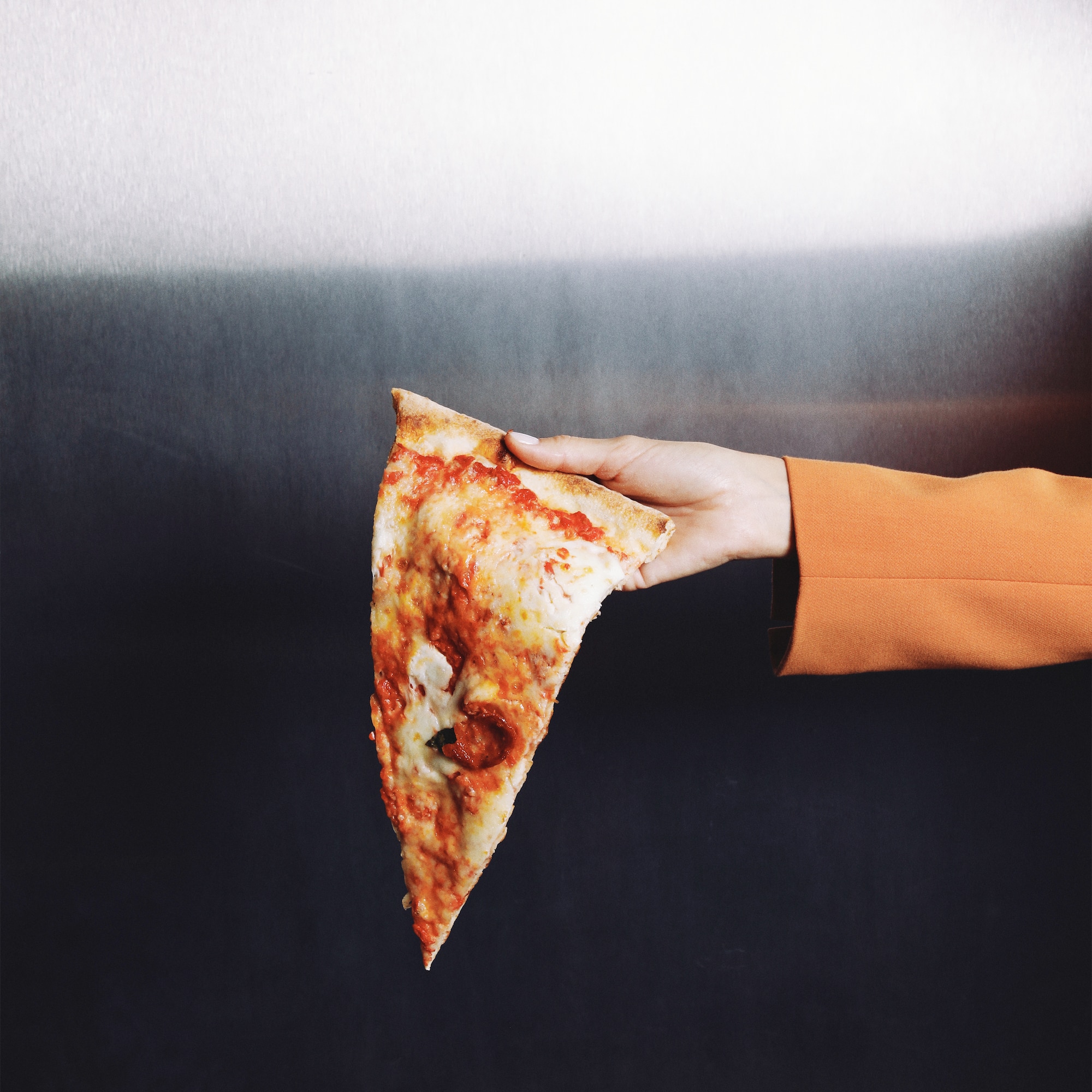 a hand holding a slice of pizza