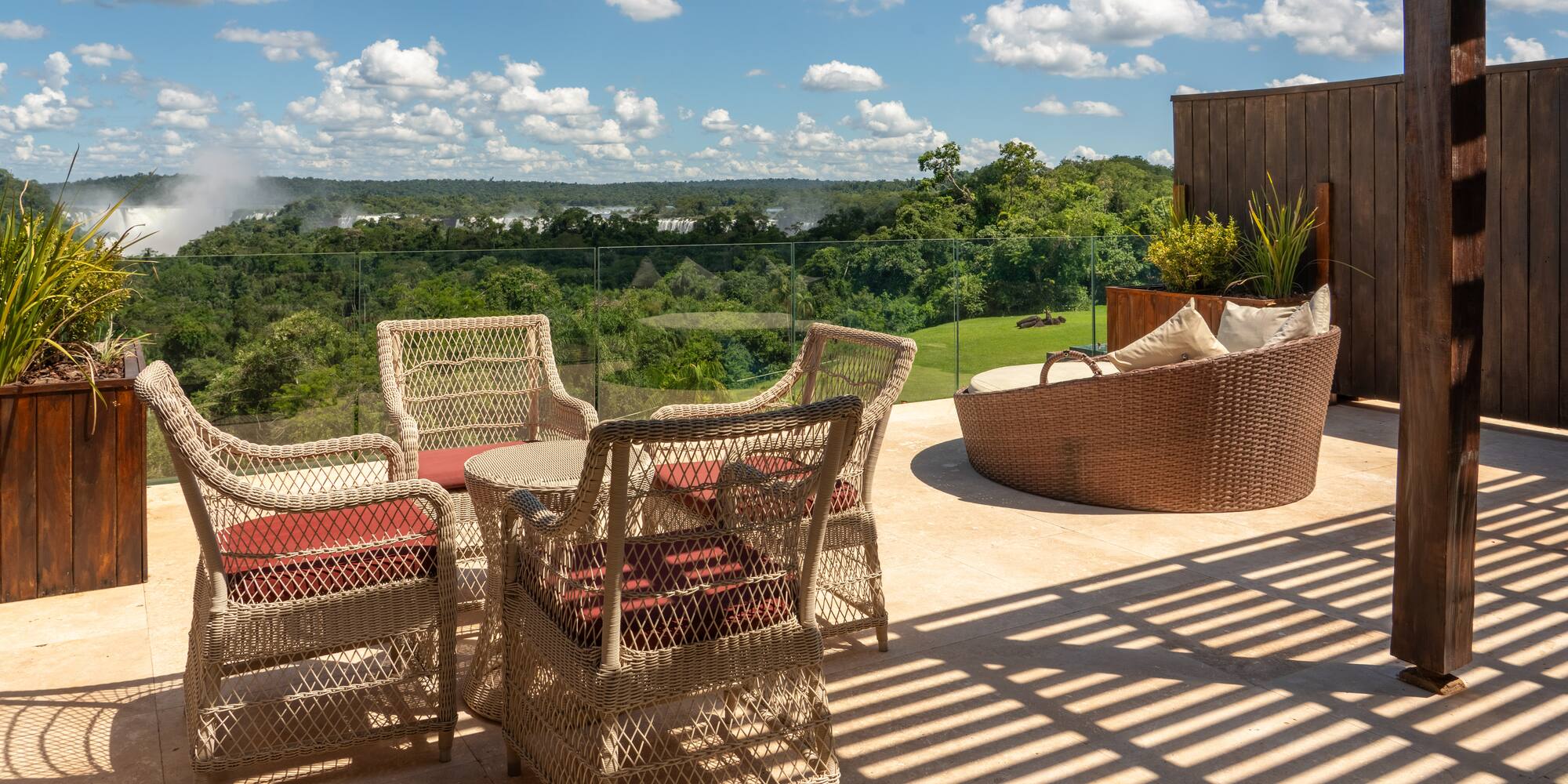 a patio with chairs and a view of the green grass and trees
