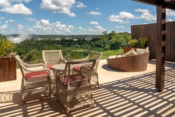 a patio with chairs and a view of the green grass and trees