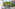 Apartment balcony with white chair, city view, green trees, and European architecture.