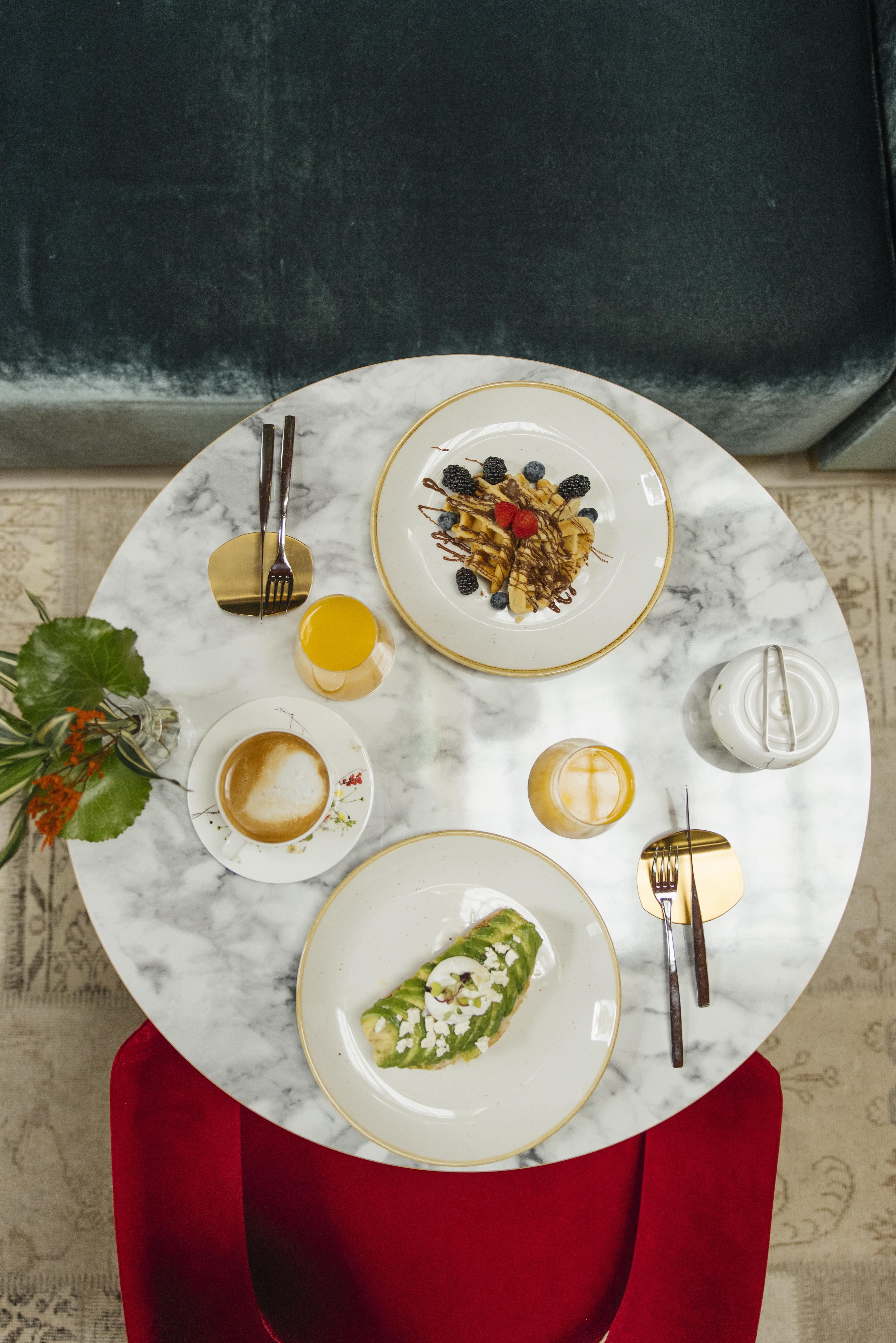 Modern brunch on marble table: waffles, avocado toast, coffee, orange juice.