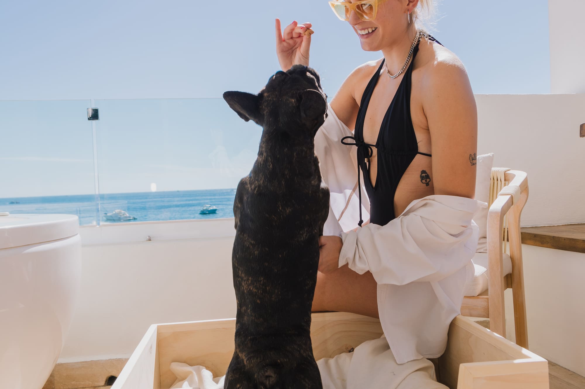 a woman in a swimsuit with a dog on a deck