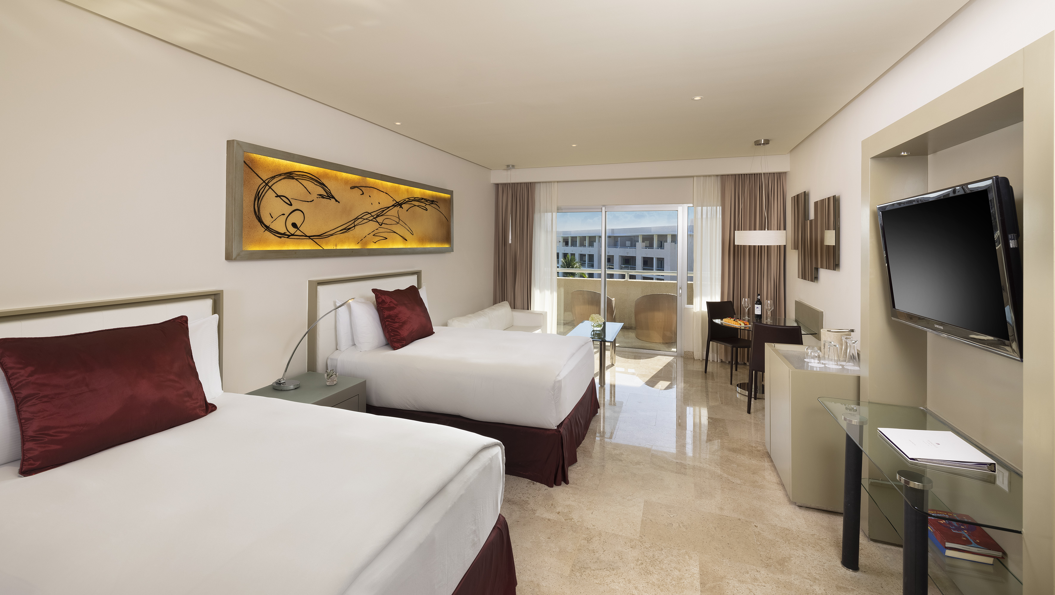 Modern hotel room with two beds, private balcony, dining area, and TV.