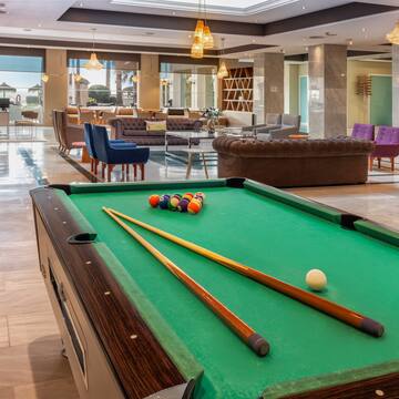 a pool table with cue sticks and balls in a room with a large window