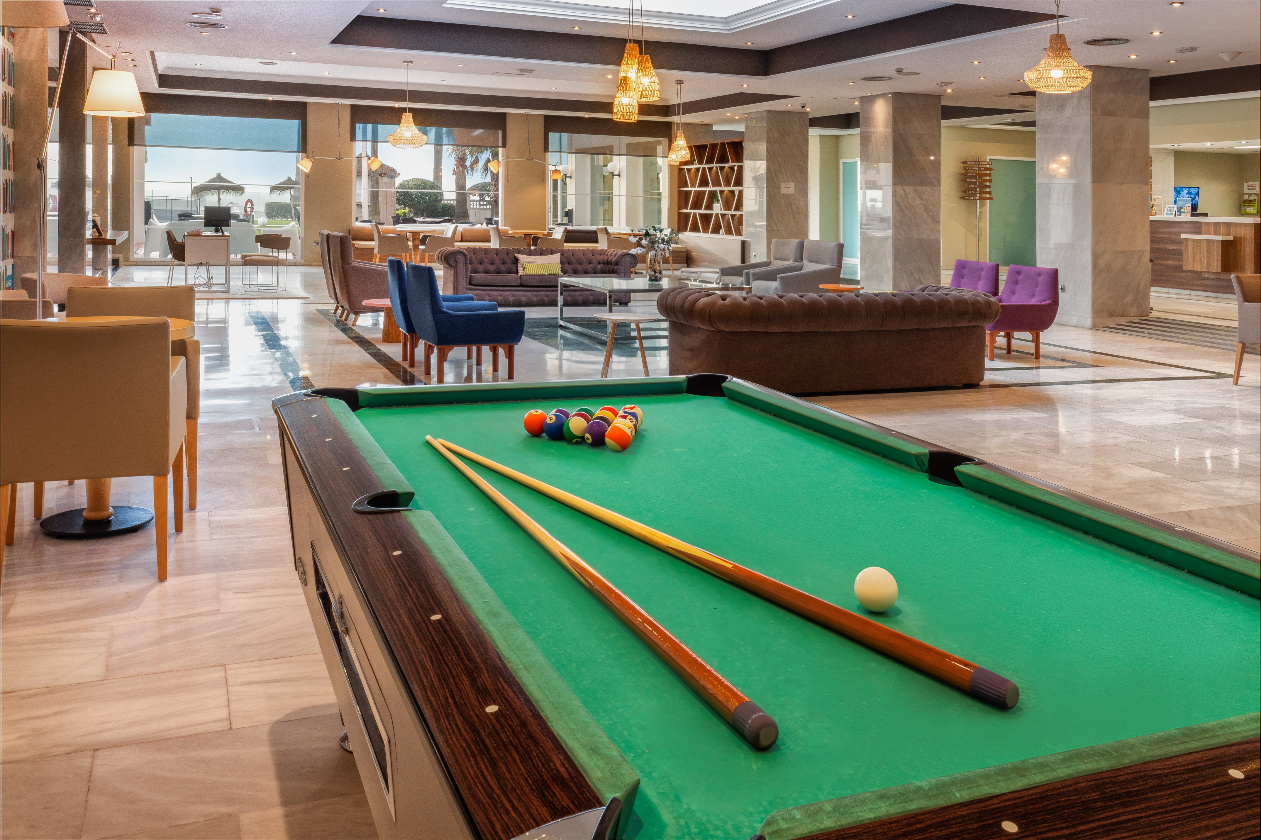 a pool table with cue sticks and balls in a room with a large window