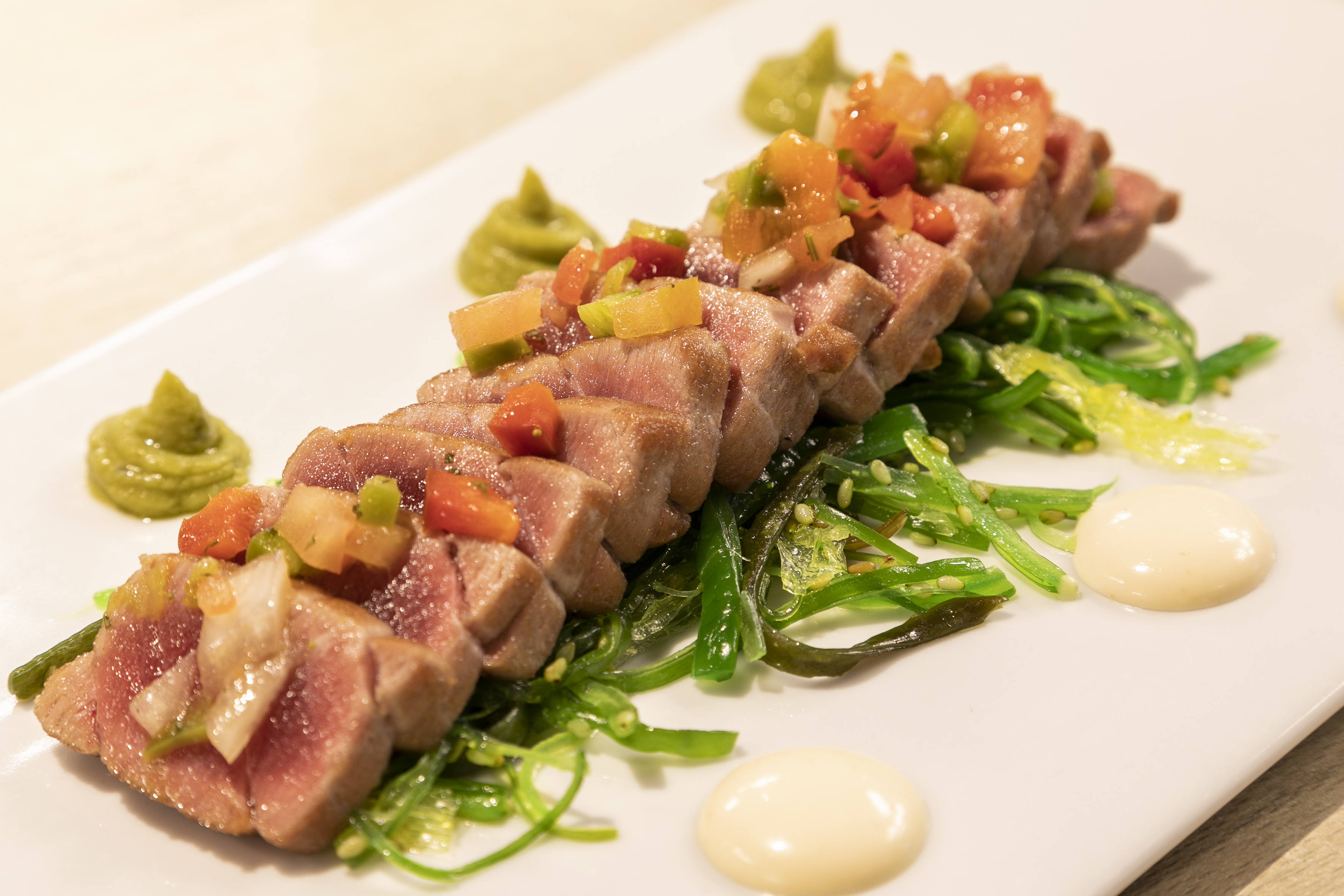 Gourmet seared tuna tataki with colorful salsa, seaweed, and sauces.