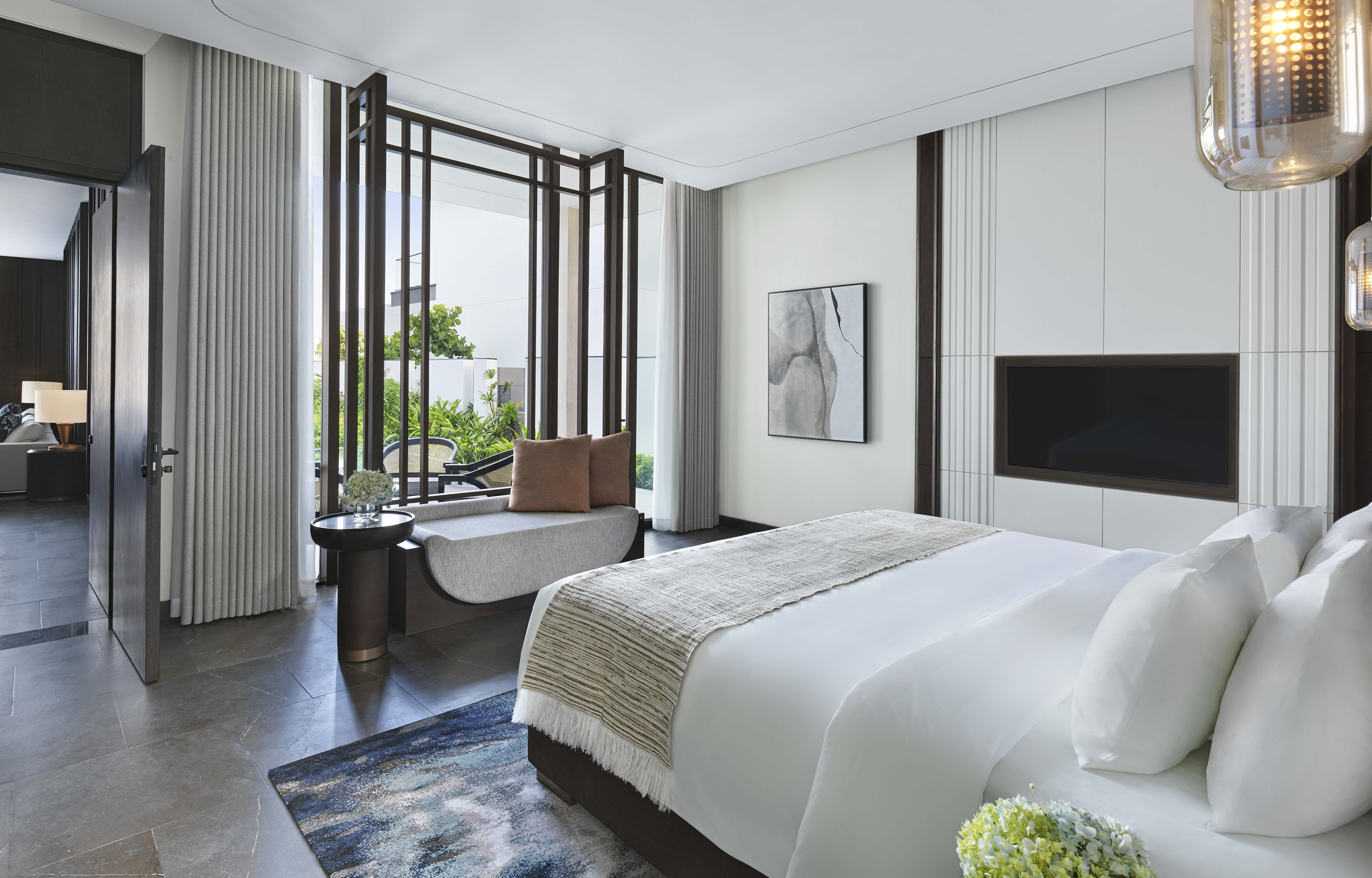Luxury bedroom with king bed, garden view, modern decor, and integrated TV.