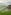 Traditional stilt hut with thatched roof overlooking green rice terraces and mountains.