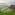 Traditional stilt hut with thatched roof overlooking green rice terraces and mountains.