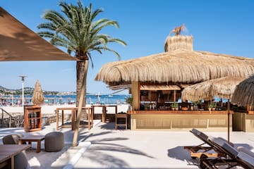 eine Strandbar mit Palmen und Stühlen