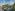 Tropical resort with large swimming pool, palm trees, and modern hotel buildings.
