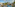 Tropical resort with large swimming pool, palm trees, and modern hotel buildings.