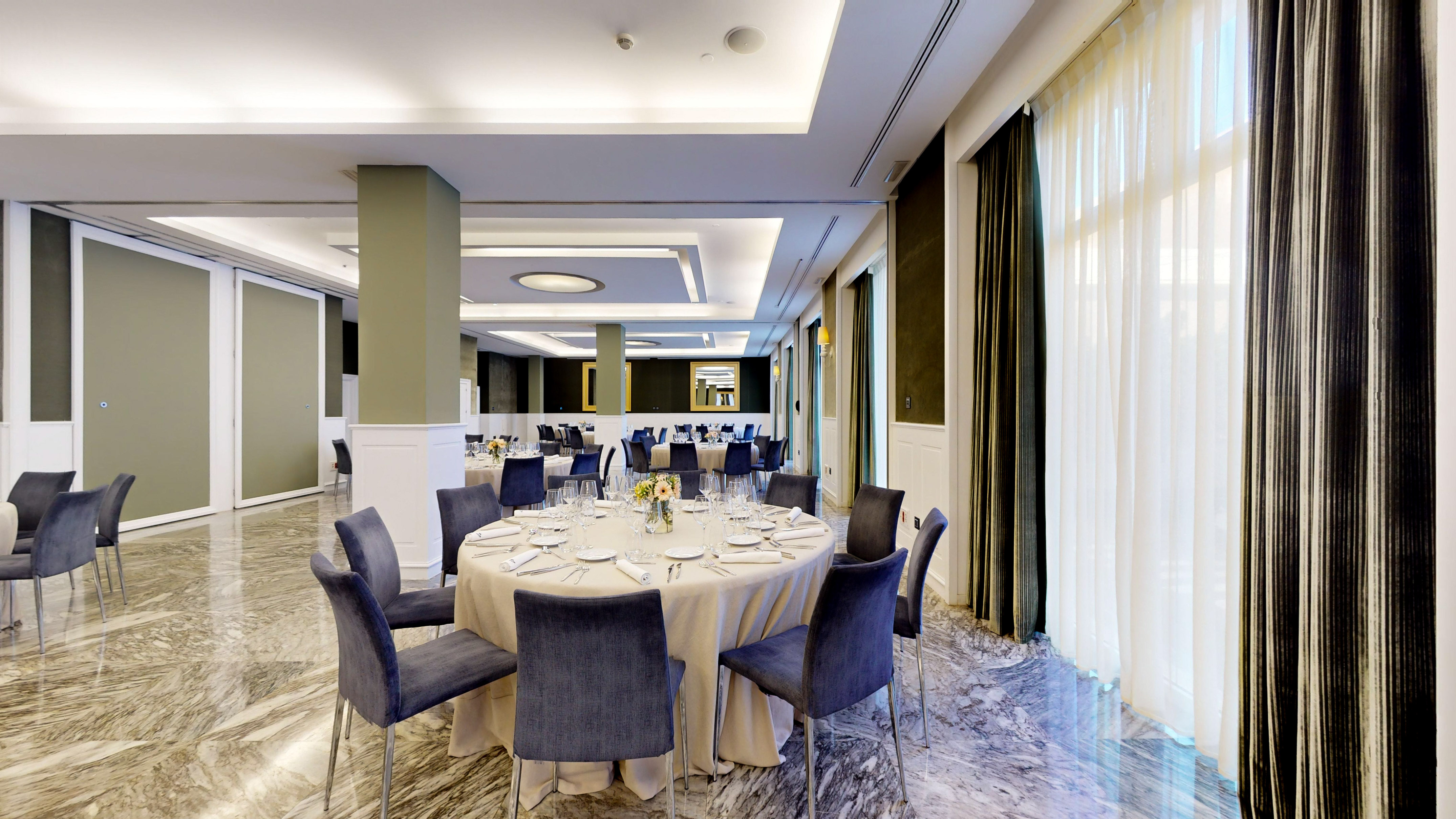 Luxury hotel dining room with set tables, blue velvet chairs, and marble floor.