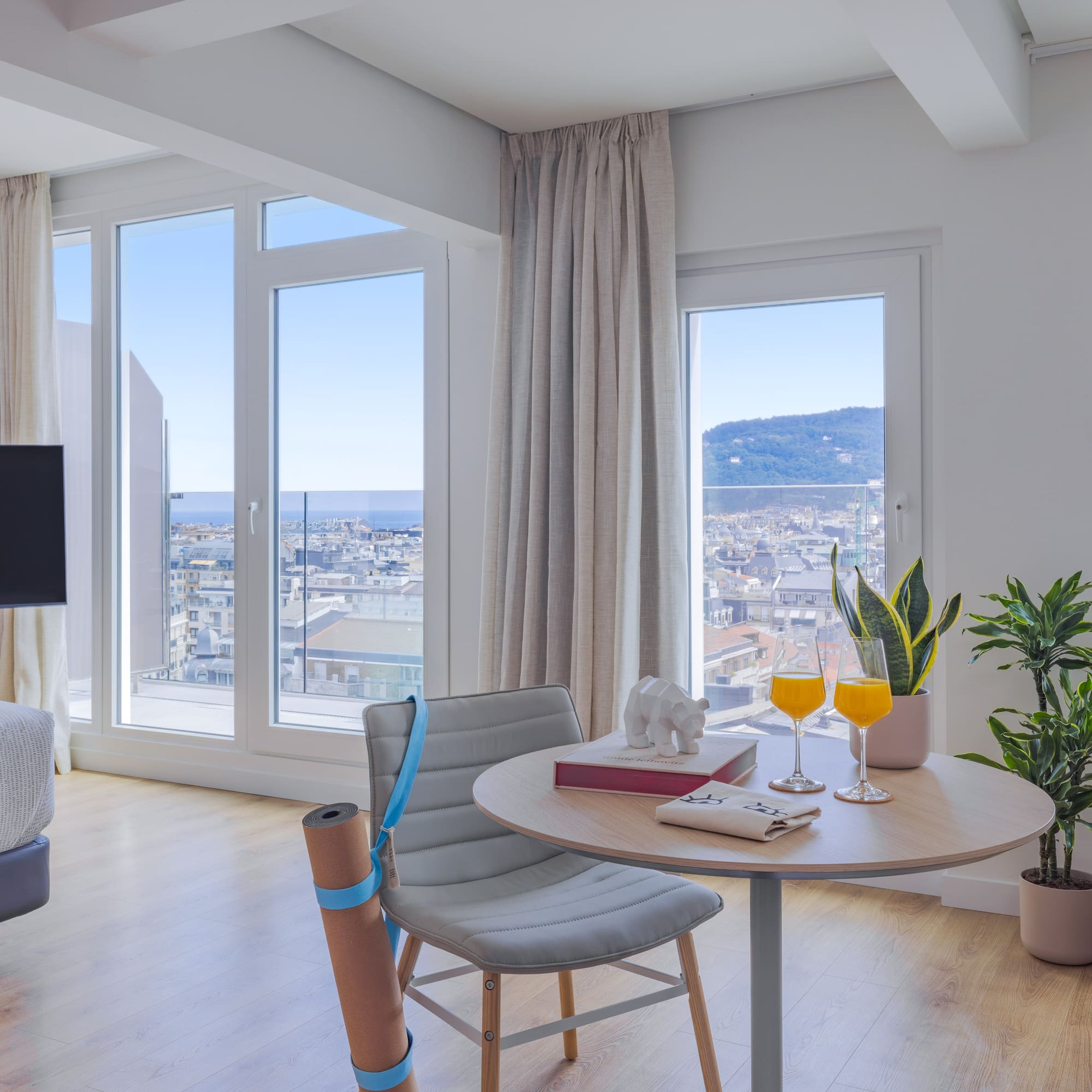 Vistas ciudad y mar desde apartamento moderno, zona yoga y mesa.