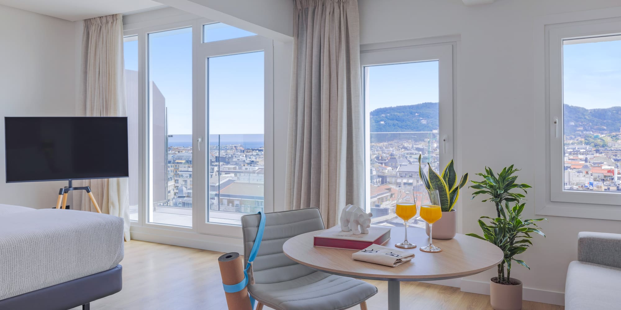 Vistas ciudad y mar desde apartamento moderno, zona yoga y mesa.