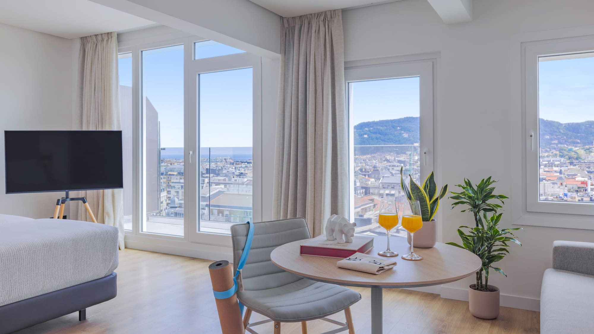 Vistas ciudad y mar desde apartamento moderno, zona yoga y mesa.