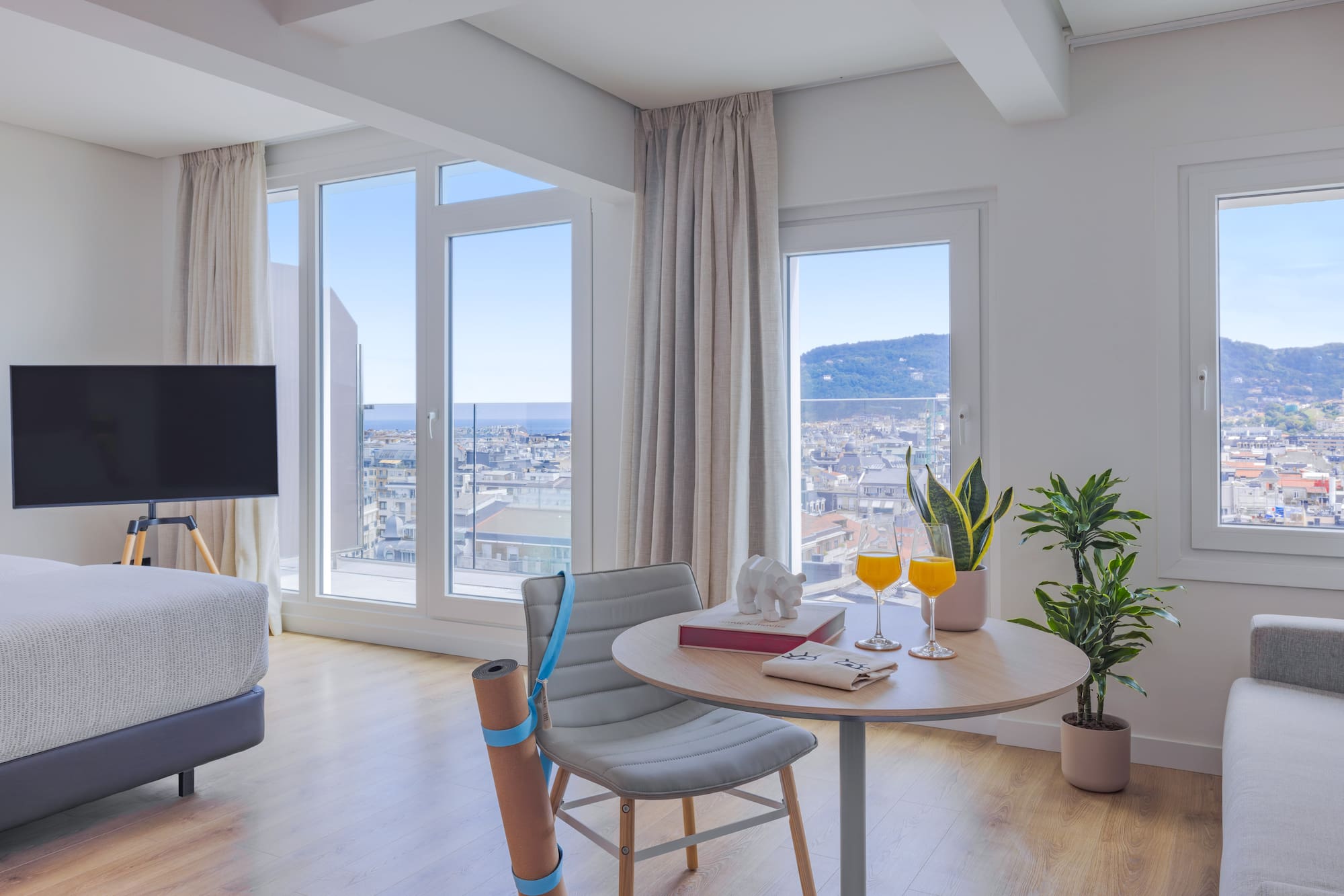 Vistas ciudad y mar desde apartamento moderno, zona yoga y mesa.