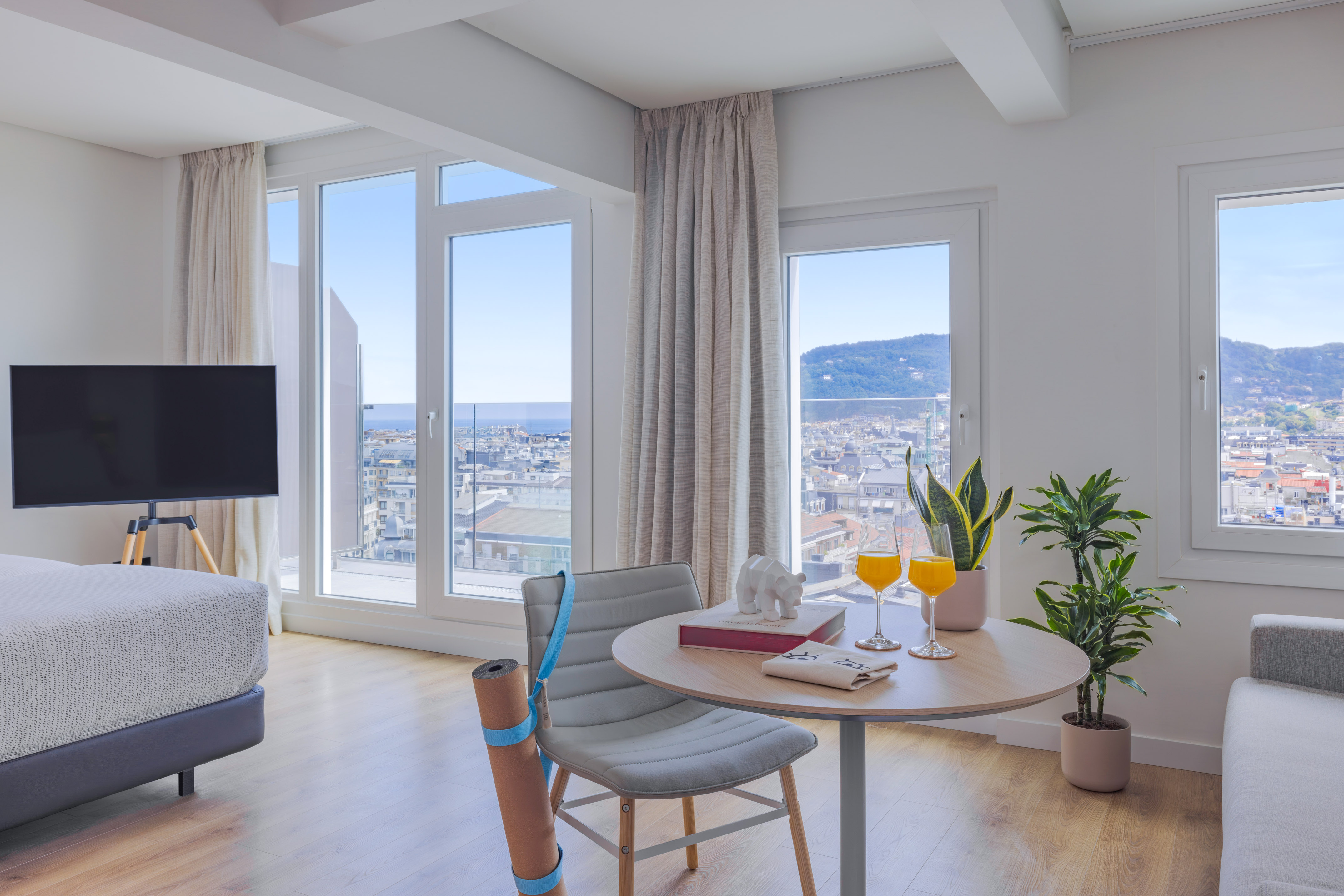 Vistas ciudad y mar desde apartamento moderno, zona yoga y mesa.