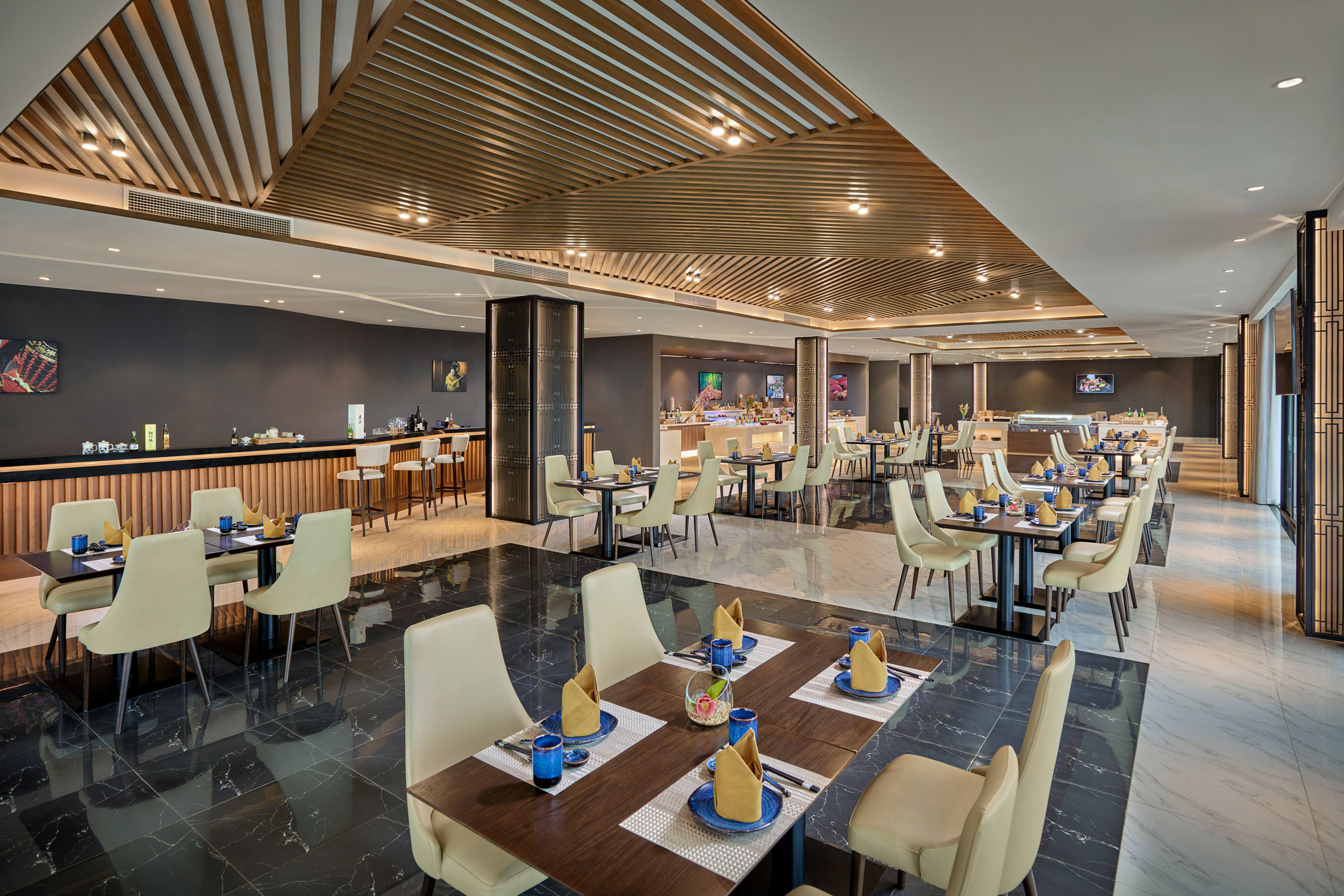 Modern restaurant dining room with tables, bar, buffet, and wooden ceiling.