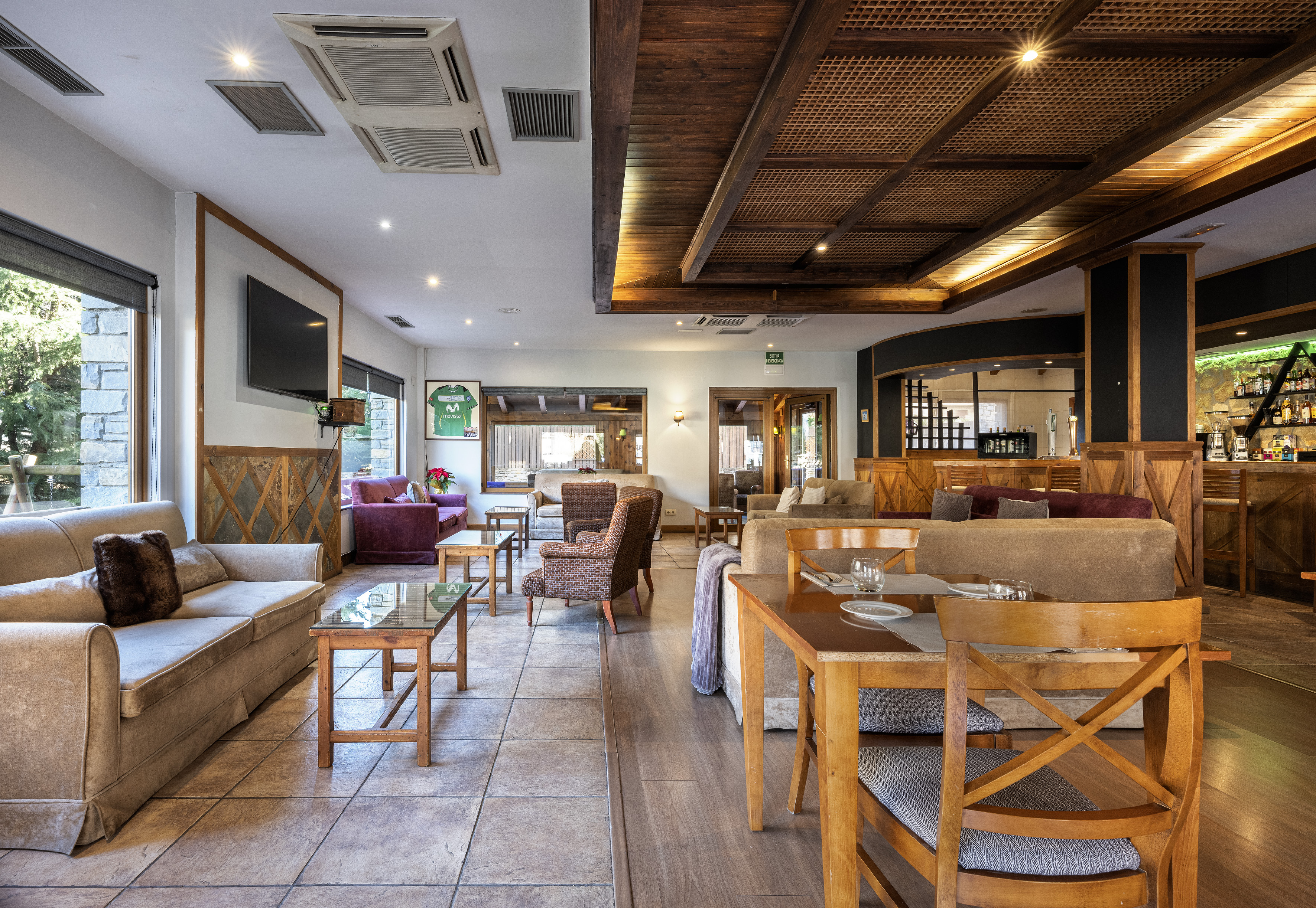 Hotel lounge and bar with cozy sofas, wooden decor, and dining tables.